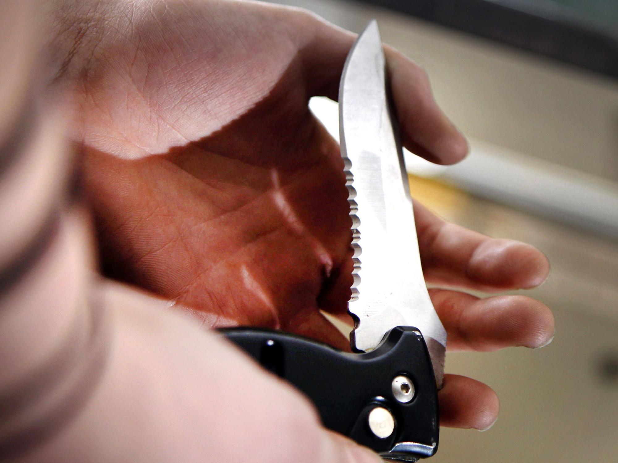 Eine Person hält ein Klappmesser mit schwarzem Griff in der Hand.