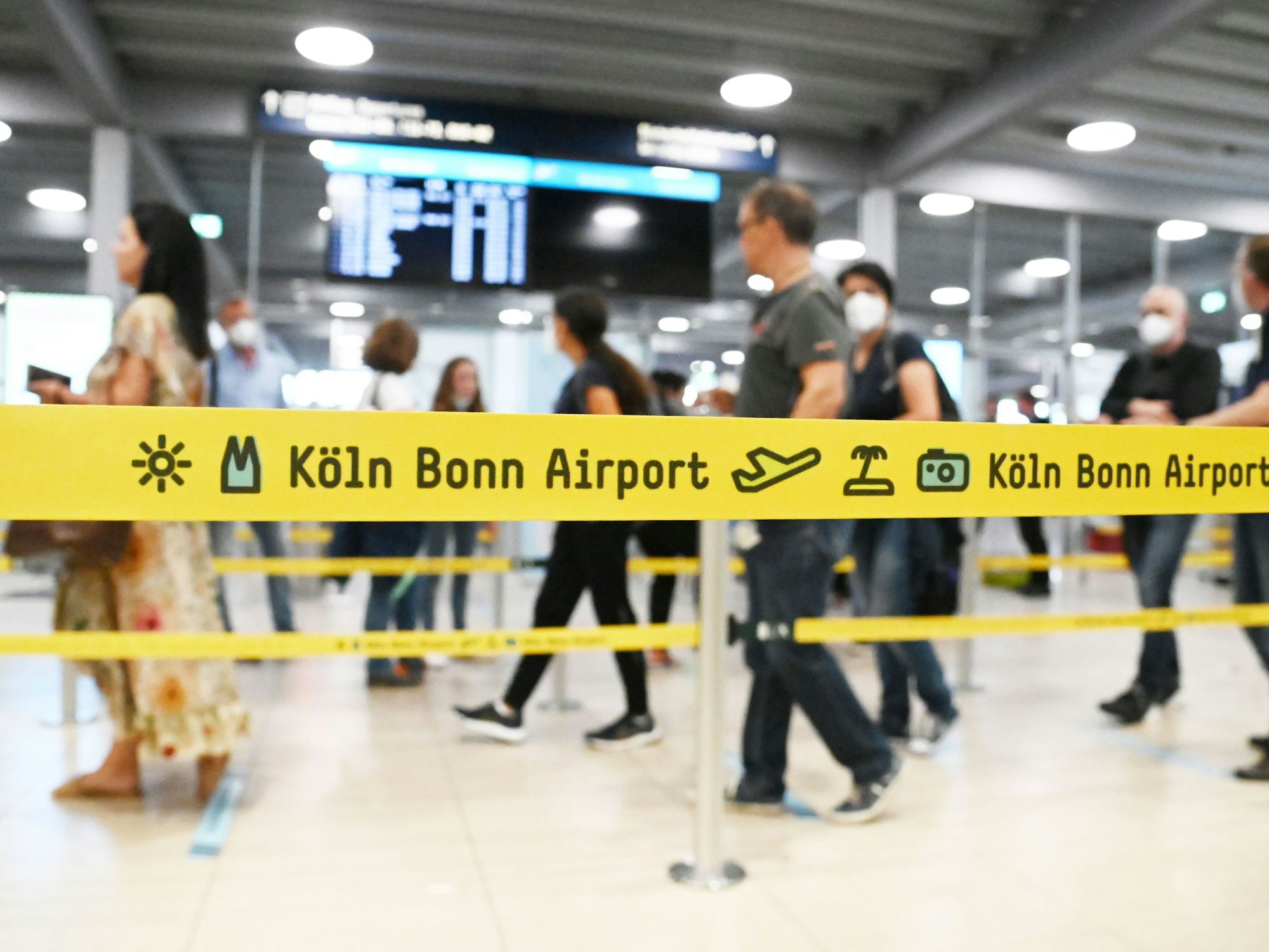Passagiere laufen am Flughafen Köln/Bonn hinter einem Absperrband her.