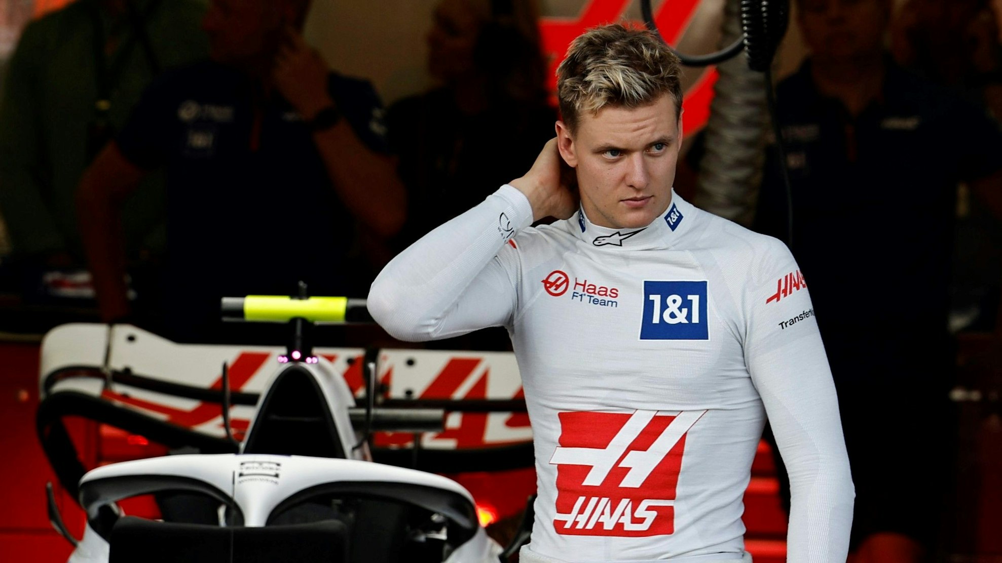 Mick Schumacher kratzt sich in der Box von Haas am Hinterkopf.