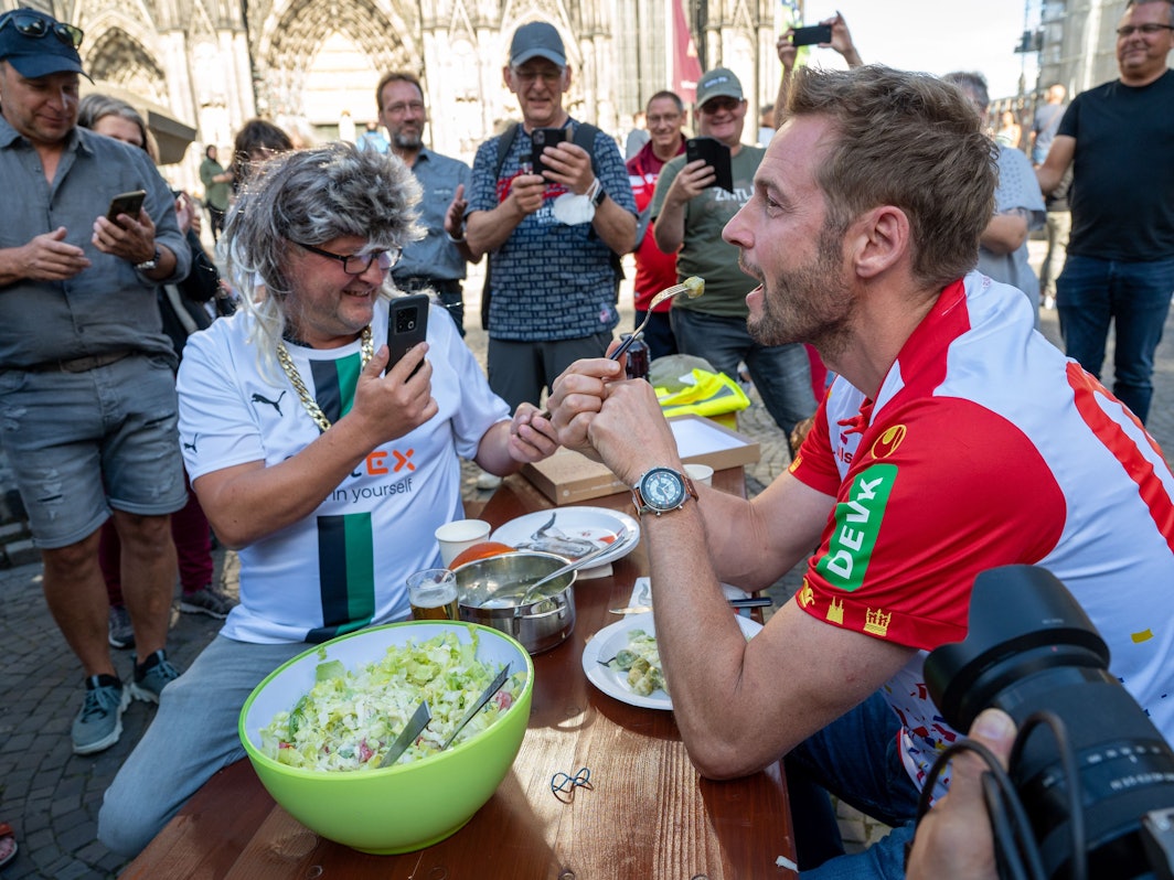 Dieter Könnes sitzt mit Markus Wipperfürth bei einer Spendenaktion auf der Kölner Domplatte.