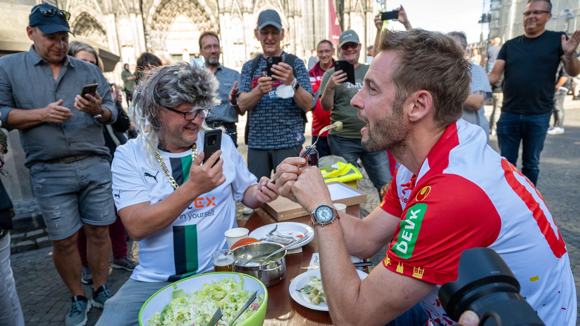 Dieter Könnes sitzt mit Markus Wipperfürth bei einer Spendenaktion auf der Kölner Domplatte.