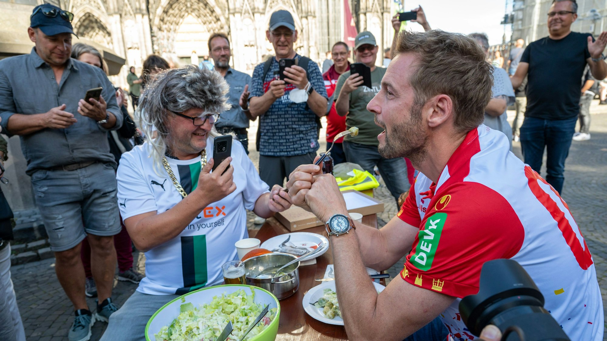 Dieter Könnes sitzt mit Markus Wipperfürth bei einer Spendenaktion auf der Kölner Domplatte.