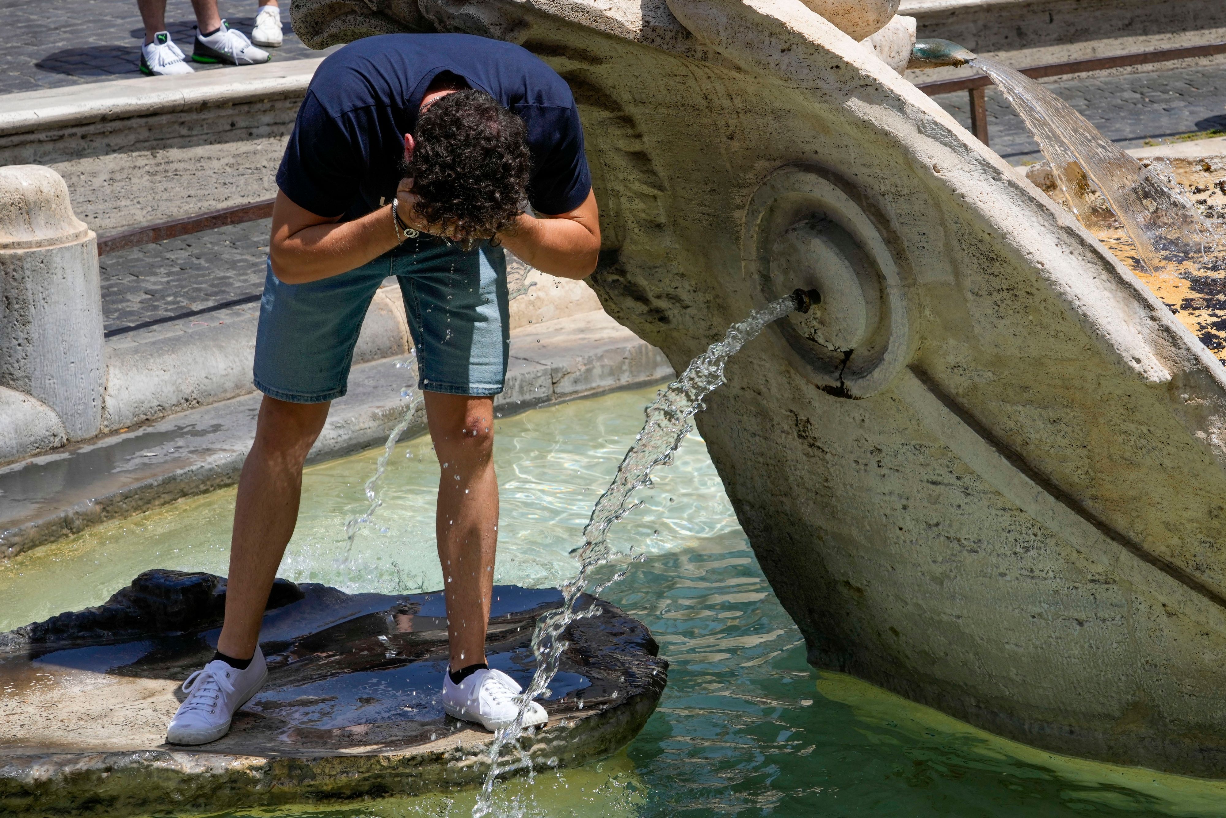 Ein Mann erfrischt sich in einem Brunnen.