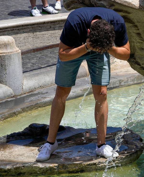 Ein Mann erfrischt sich in einem Brunnen.