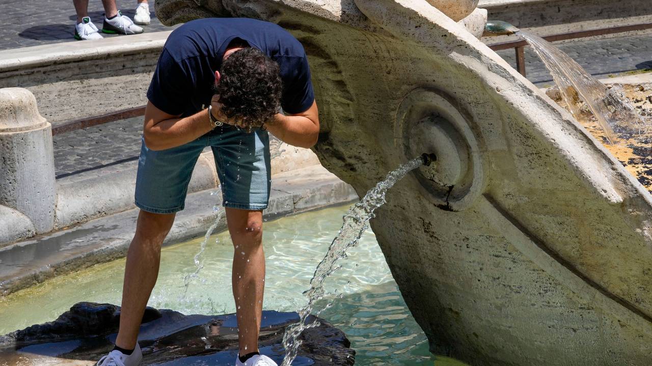 Ein Mann erfrischt sich in einem Brunnen.
