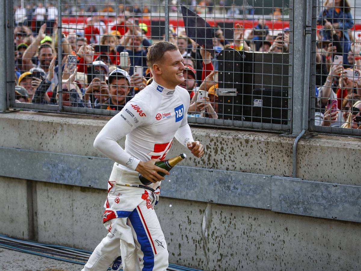 Mick Schumacher läuft mit einer Champagner-Flasche zu den Fans.