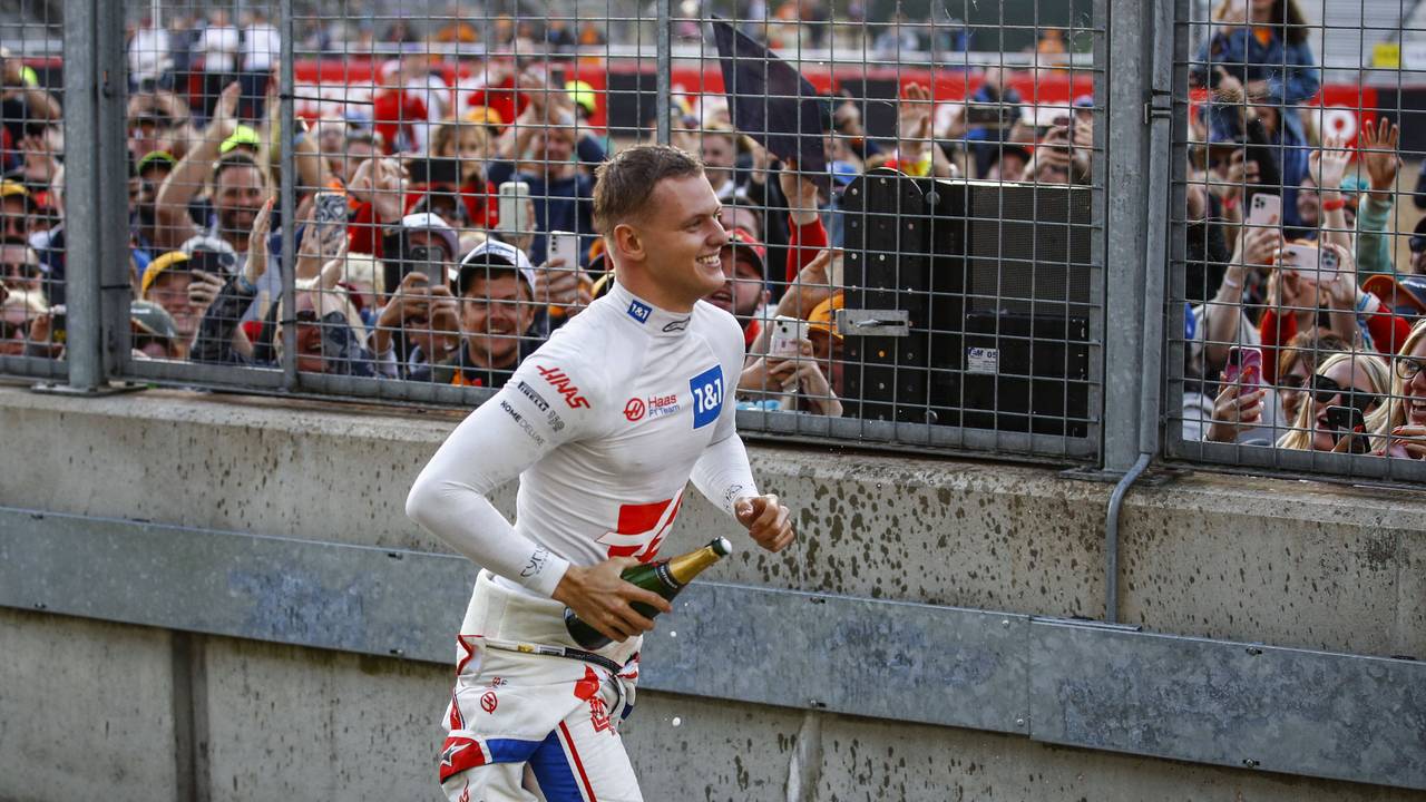 Mick Schumacher läuft mit einer Champagner-Flasche zu den Fans.