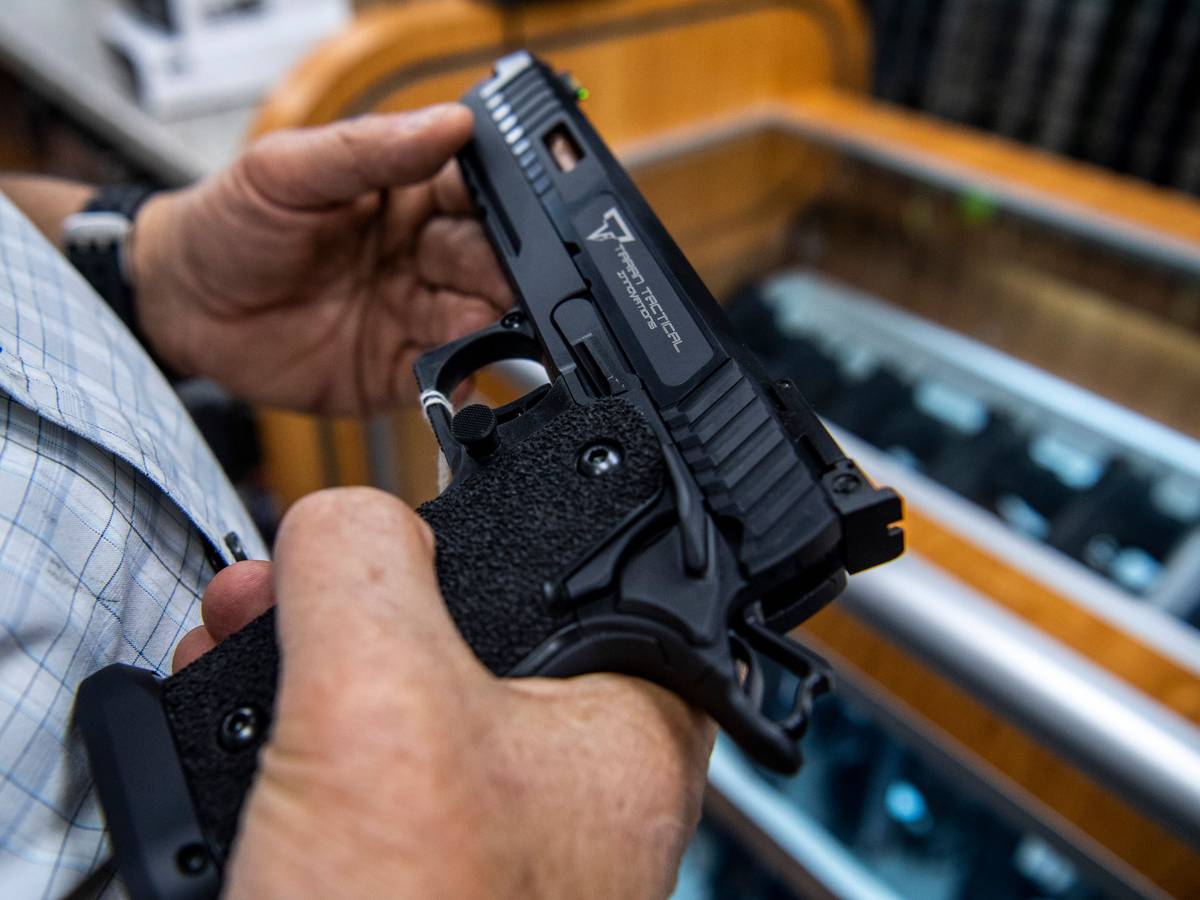 Ein Kunde prüft eine Handfeuerwaffe, die zum Verkauf steht und bei SP firearms ausgestellt ist.