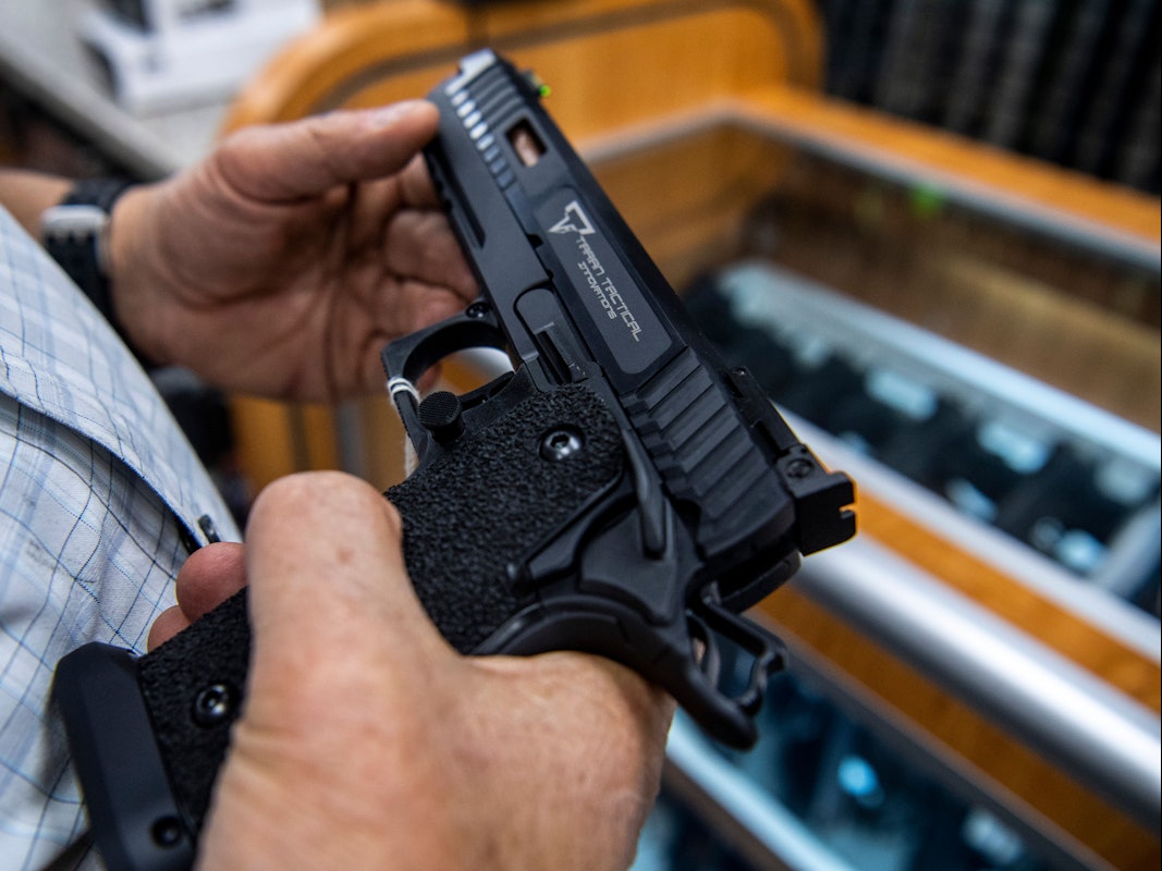 Ein Kunde prüft eine Handfeuerwaffe, die zum Verkauf steht und bei SP firearms ausgestellt ist.