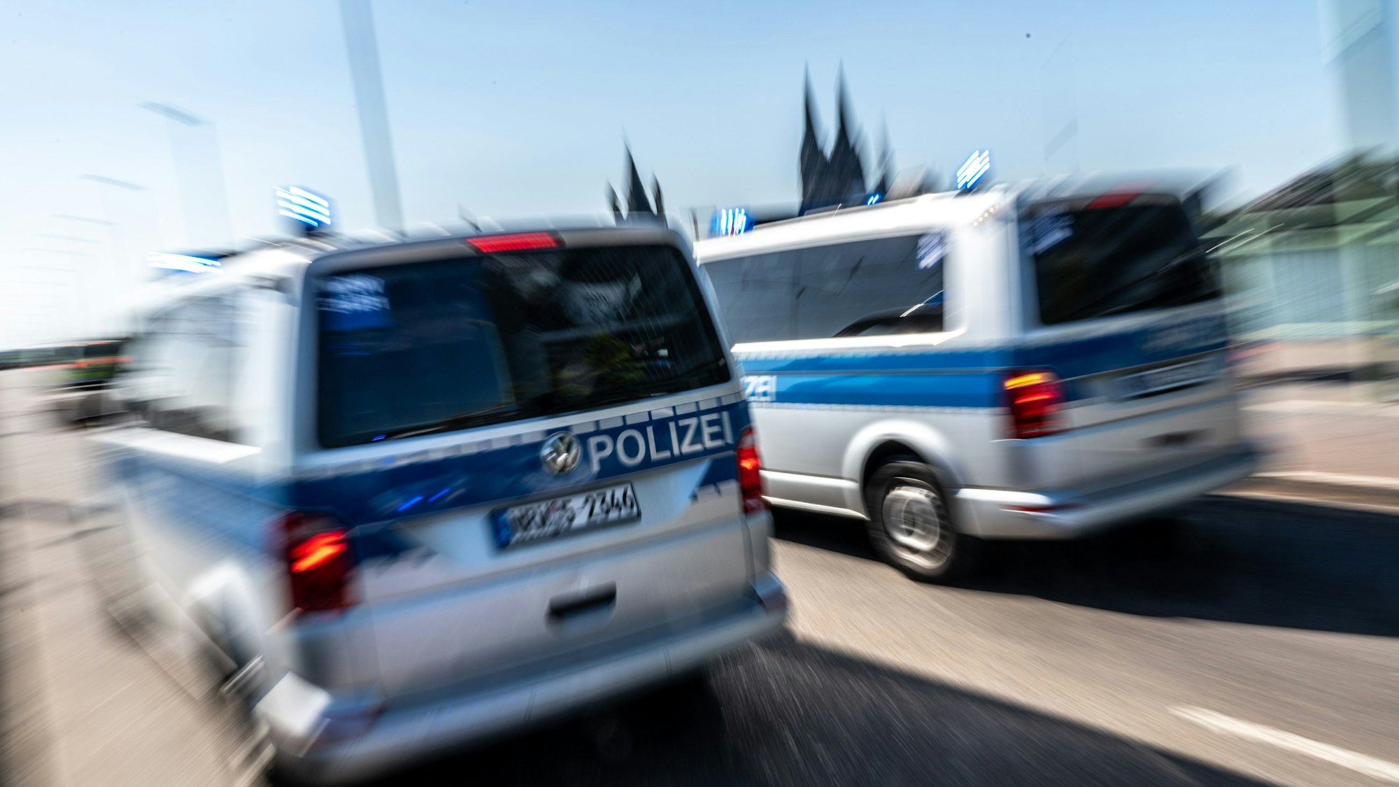 Polizeifahrzeuge fahren mit Blaulicht über die Deutzer Brücke in Köln.