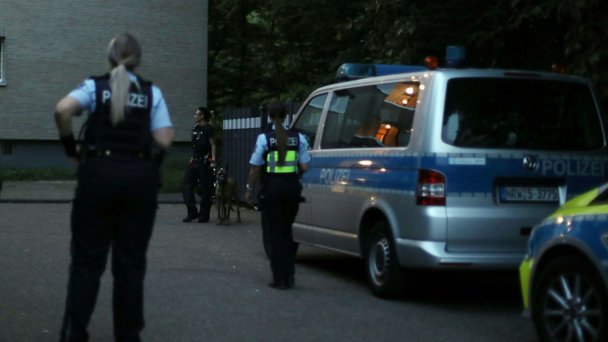 Polizisten und Polizistinnen stehen bei einem Großeinsatz vor einem Wohnhaus in Köln Ostheim.