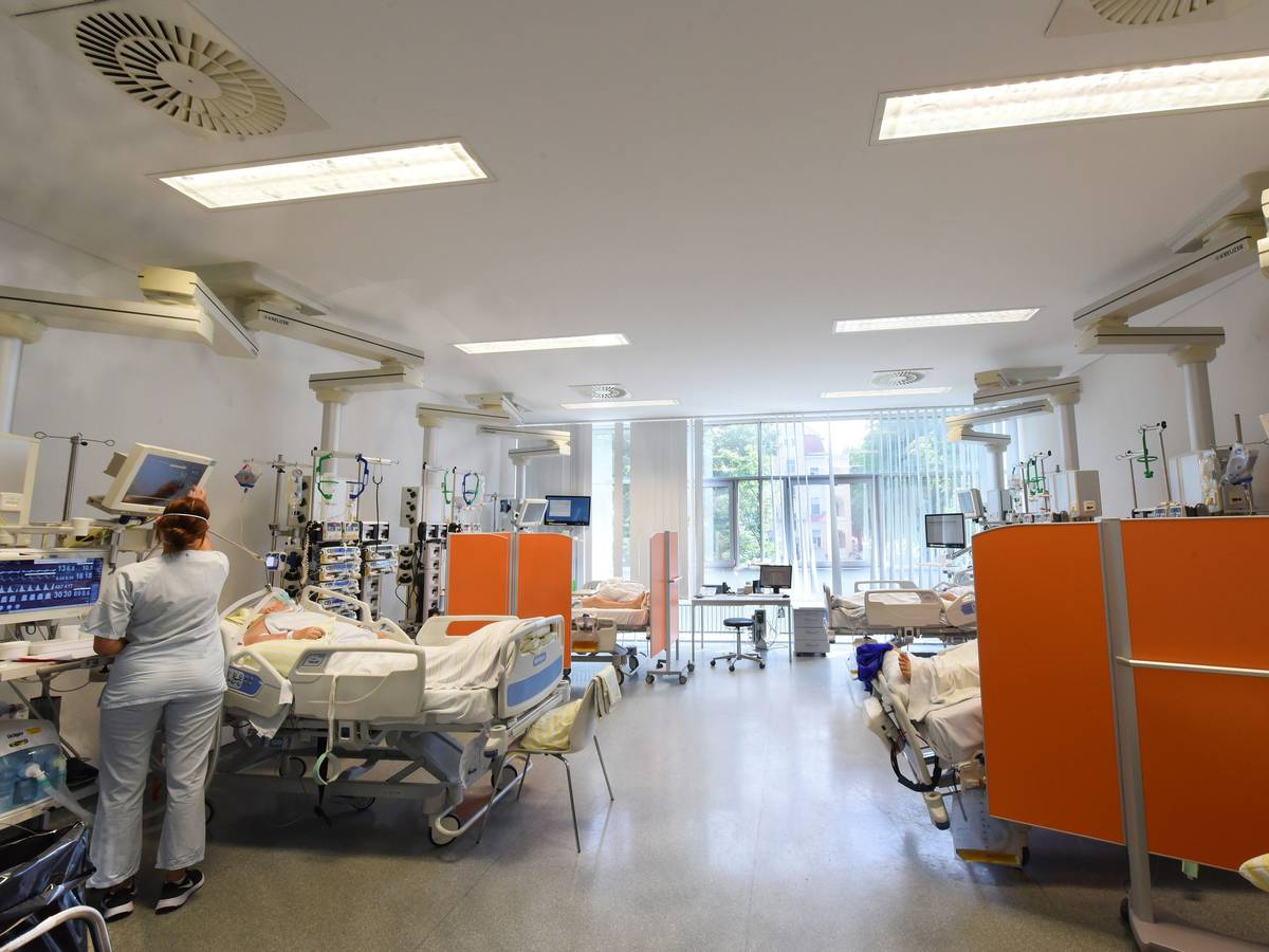 Auf der Intensivtherapie-Station (ITS) in einer Klinik in Sachsen steht eine Mitarbeiterin am Bett einer Patientin.
