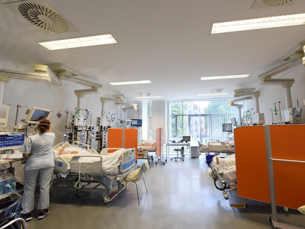 Auf der Intensivtherapie-Station (ITS) in einer Klinik in Sachsen steht eine Mitarbeiterin am Bett einer Patientin.