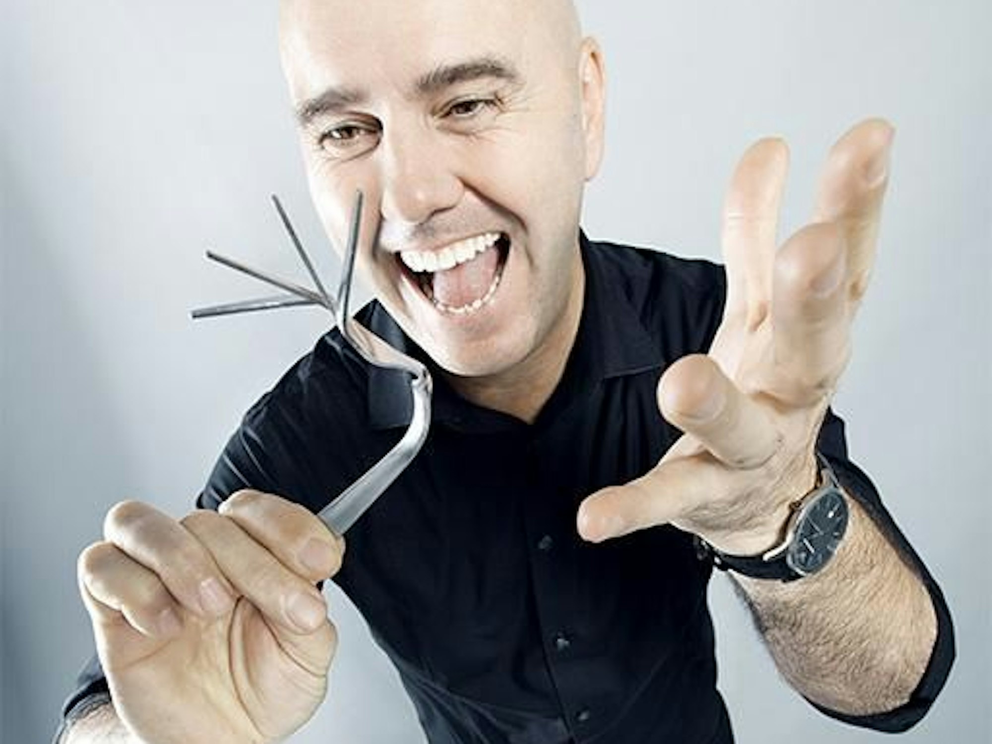 Zauberkünstler Giovanni Alecci schaut auf eine verbogene Gabel.