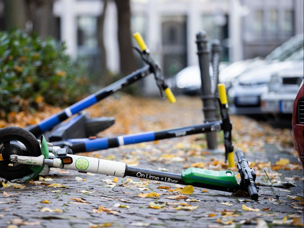 E-Scooter liegen auf einem Gehweg und versperren den Weg.