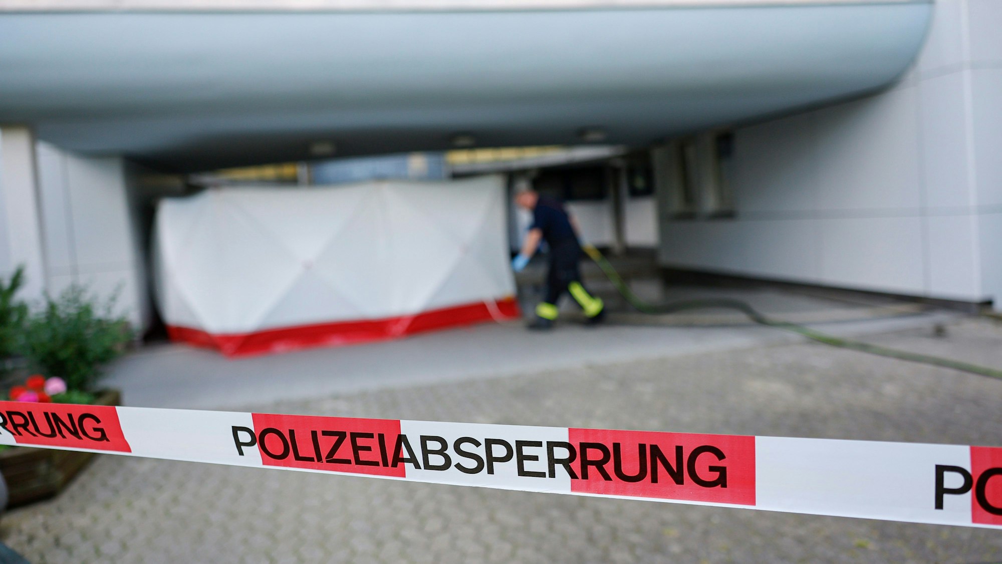 Eine Polizeiabsperrung ist um den Eingang zu einem Hochhaus gespannt, nachdem ein Kind und eine Frau vermutlich bei einem Sturz aus dem Gebäude ums Leben gekommen sind.