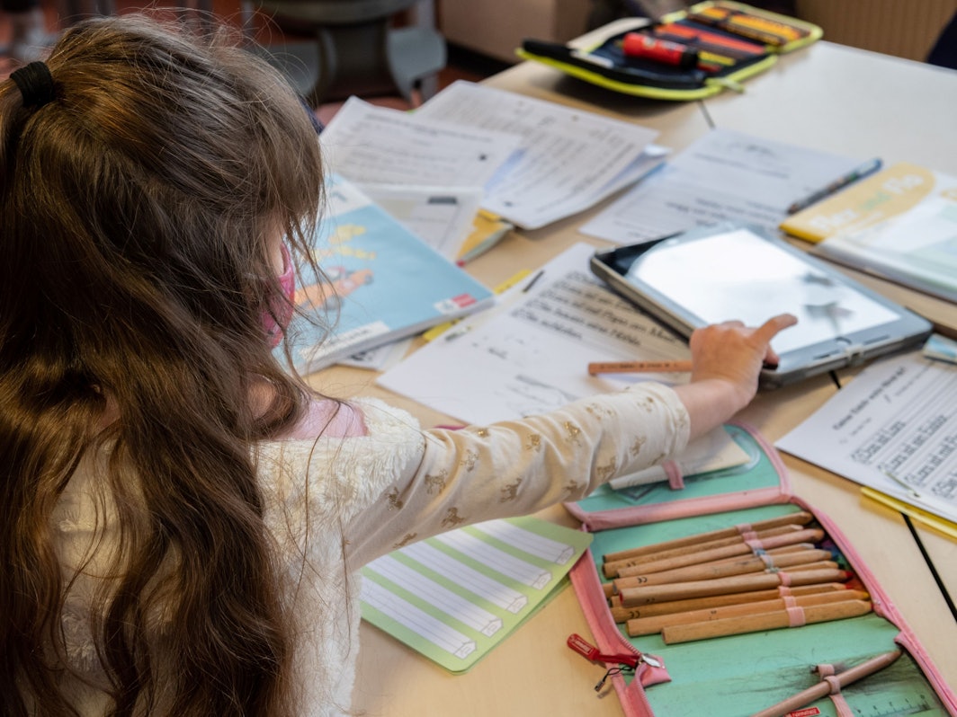 Eine Grundschülerin arbeitet im Klassenraum an ihren Schulaufgaben.