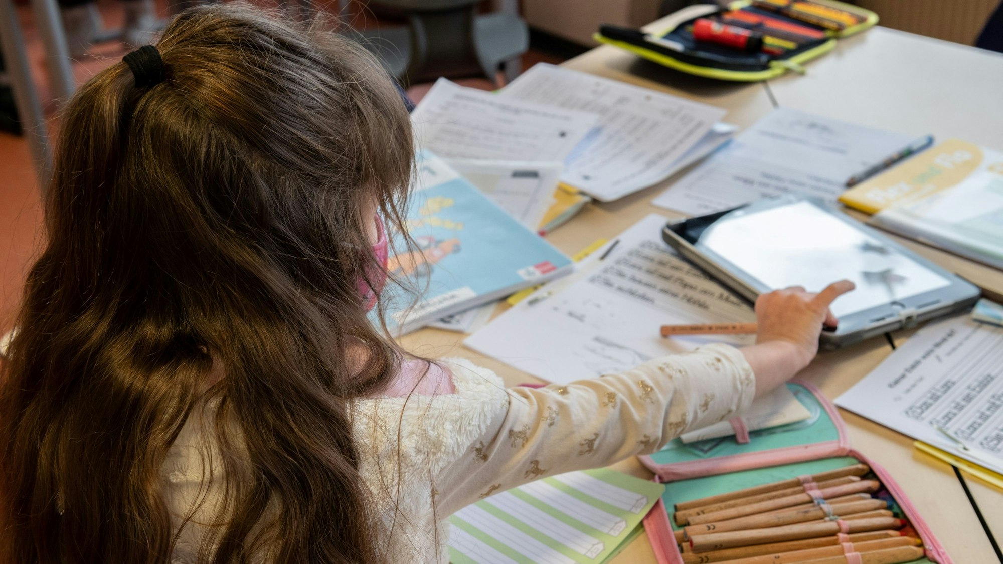 Eine Grundschülerin arbeitet im Klassenraum an ihren Schulaufgaben.