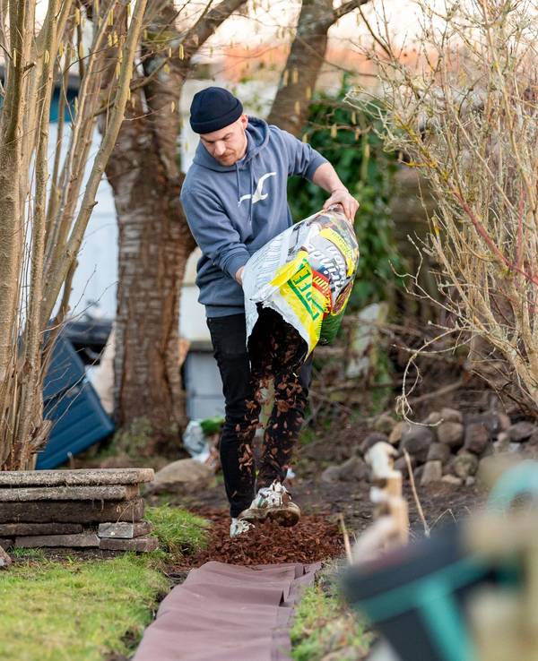 Jean Hinz verteilt Rindenmulch auf einem neu angelegten Weg in seinem Kleingarten in Lüneburg. Das Foto wurde Ende Februar 2021 aufgenommen. In der Corona-Krise hat das Interesse am Kleingarten stark zugenommen. Vor allem in den Städten ist die Nachfrage groß.