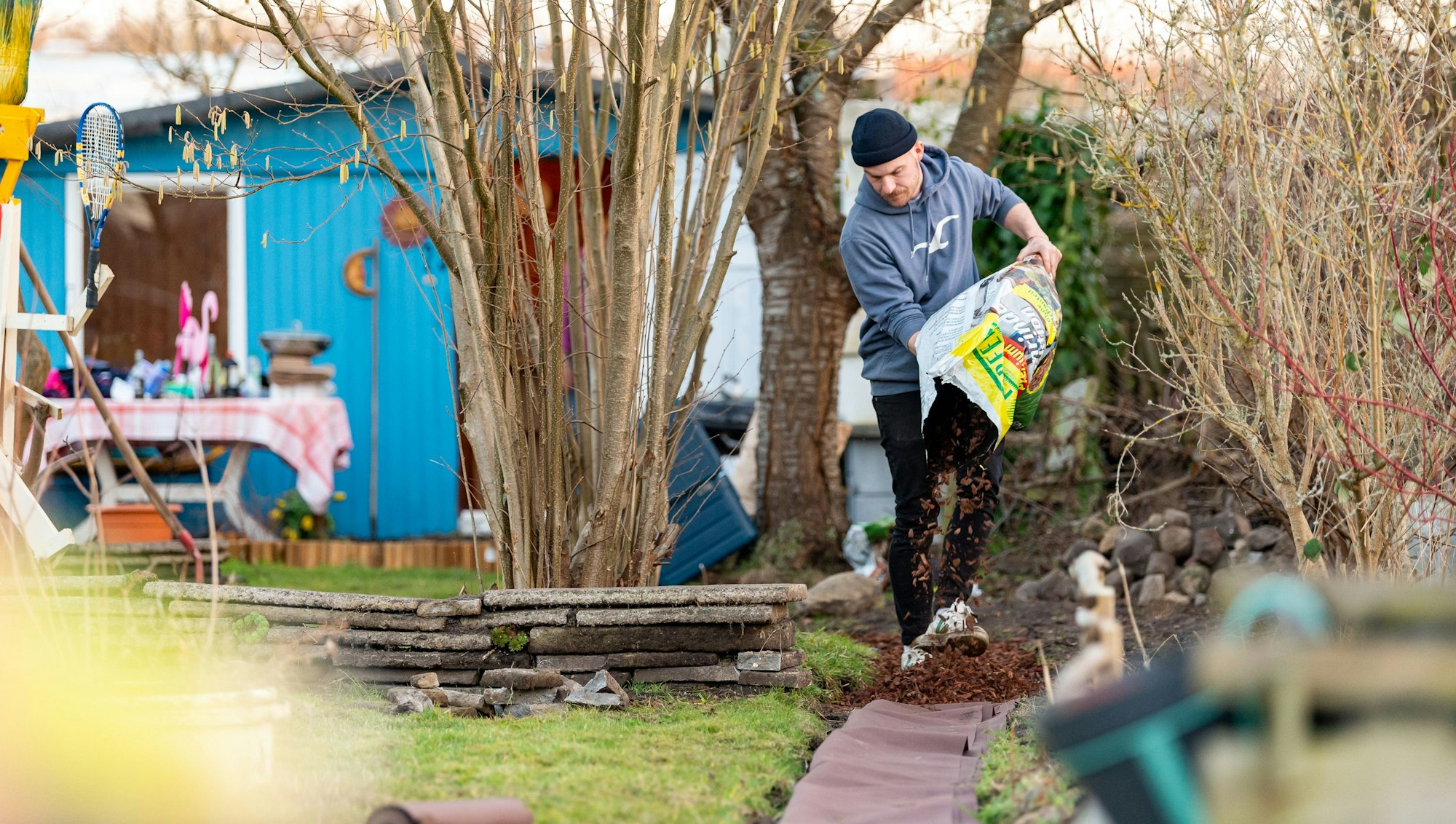 Jean Hinz verteilt Rindenmulch auf einem neu angelegten Weg in seinem Kleingarten in Lüneburg. Das Foto wurde Ende Februar 2021 aufgenommen. In der Corona-Krise hat das Interesse am Kleingarten stark zugenommen. Vor allem in den Städten ist die Nachfrage groß.