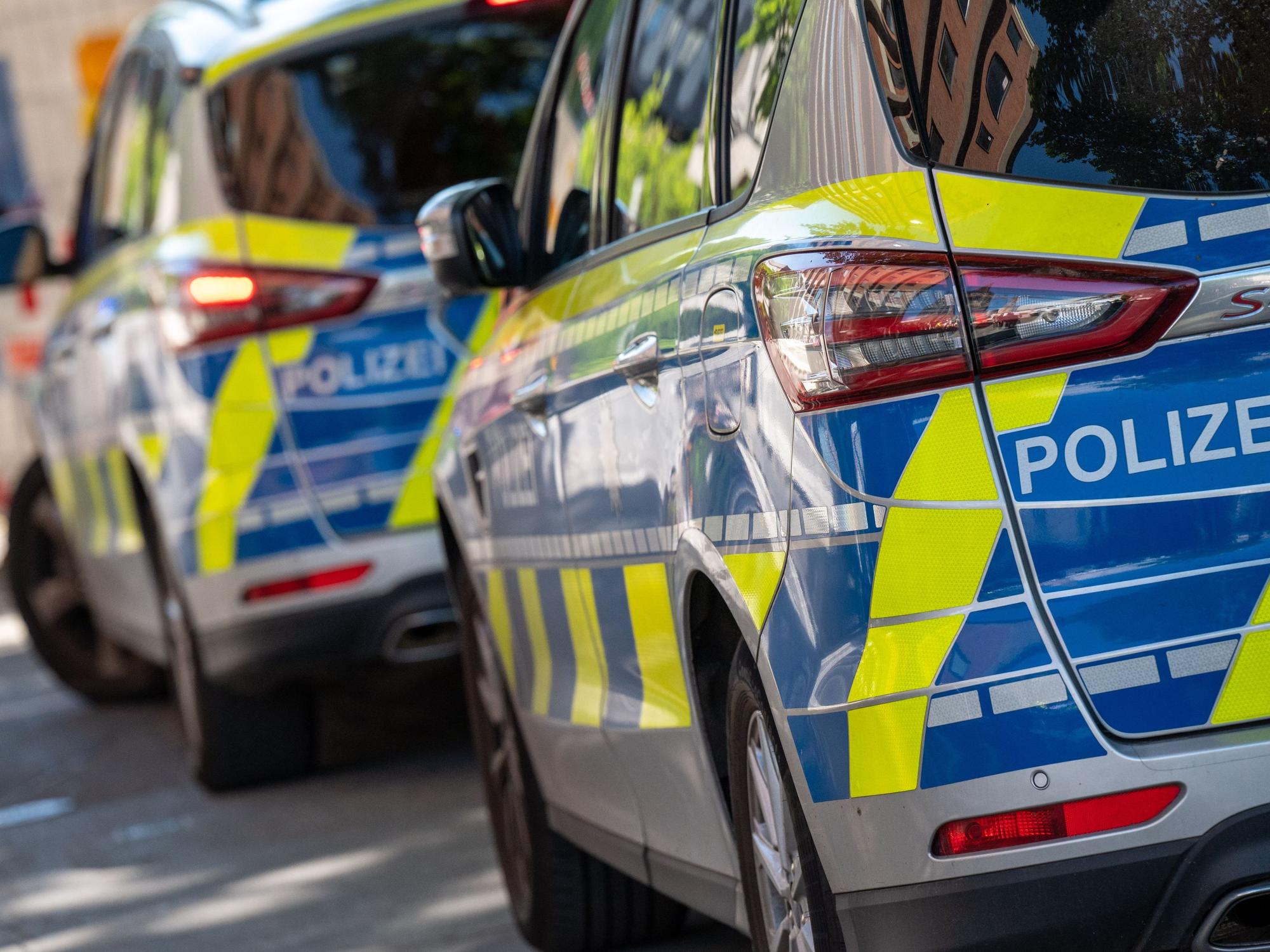 Zwei Polizeifahrzeuge stehen hintereinander auf der Straße.