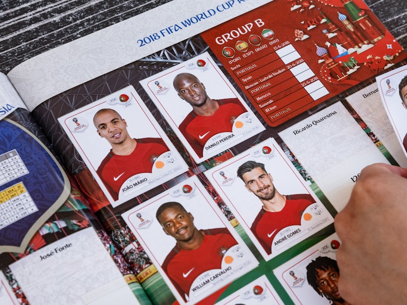 Eine Frau klebt Panini-Sammelbilder in ein Stickeralbum