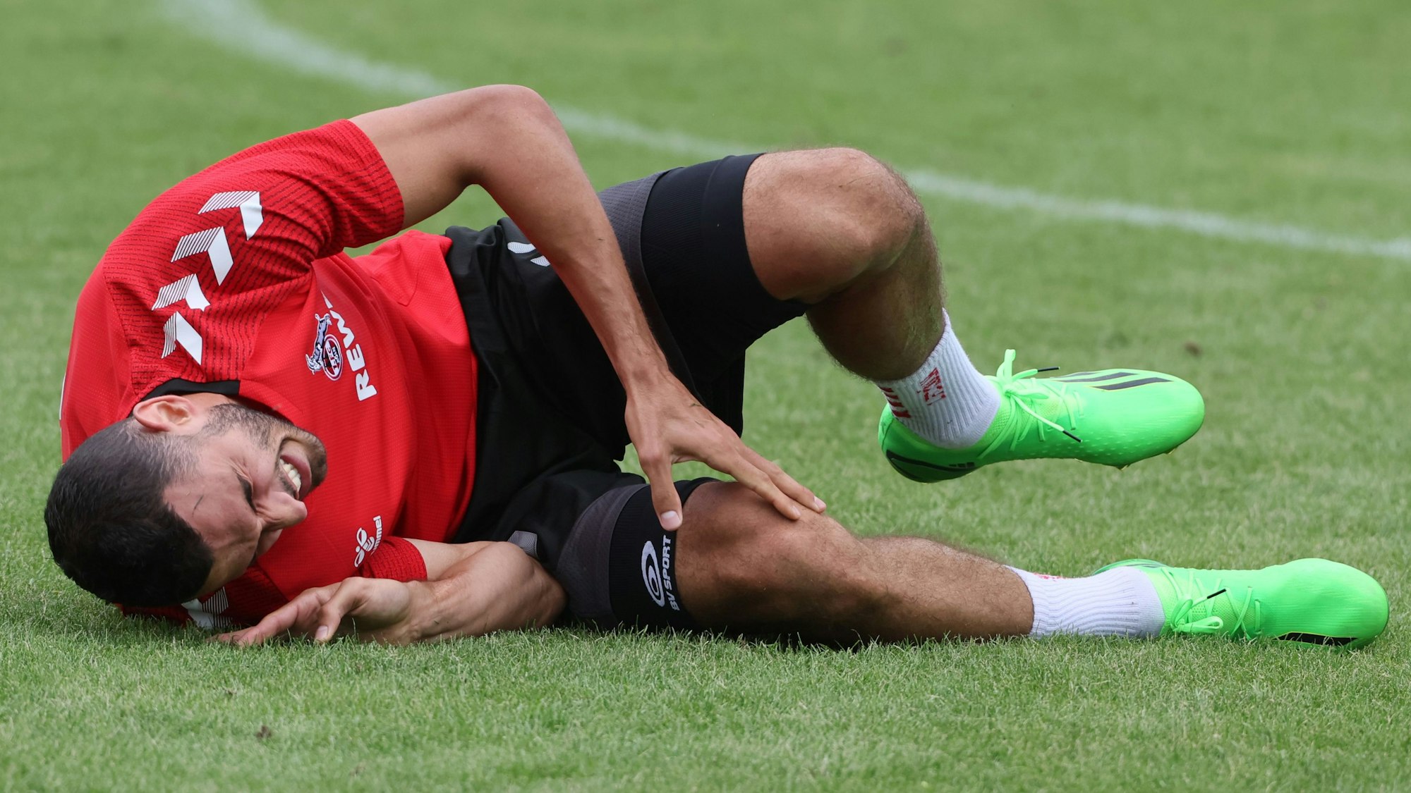 Ellyes Skhiri liegt im Trainingslager des 1. FC Köln in Donaueschingen auf dem Rasen.