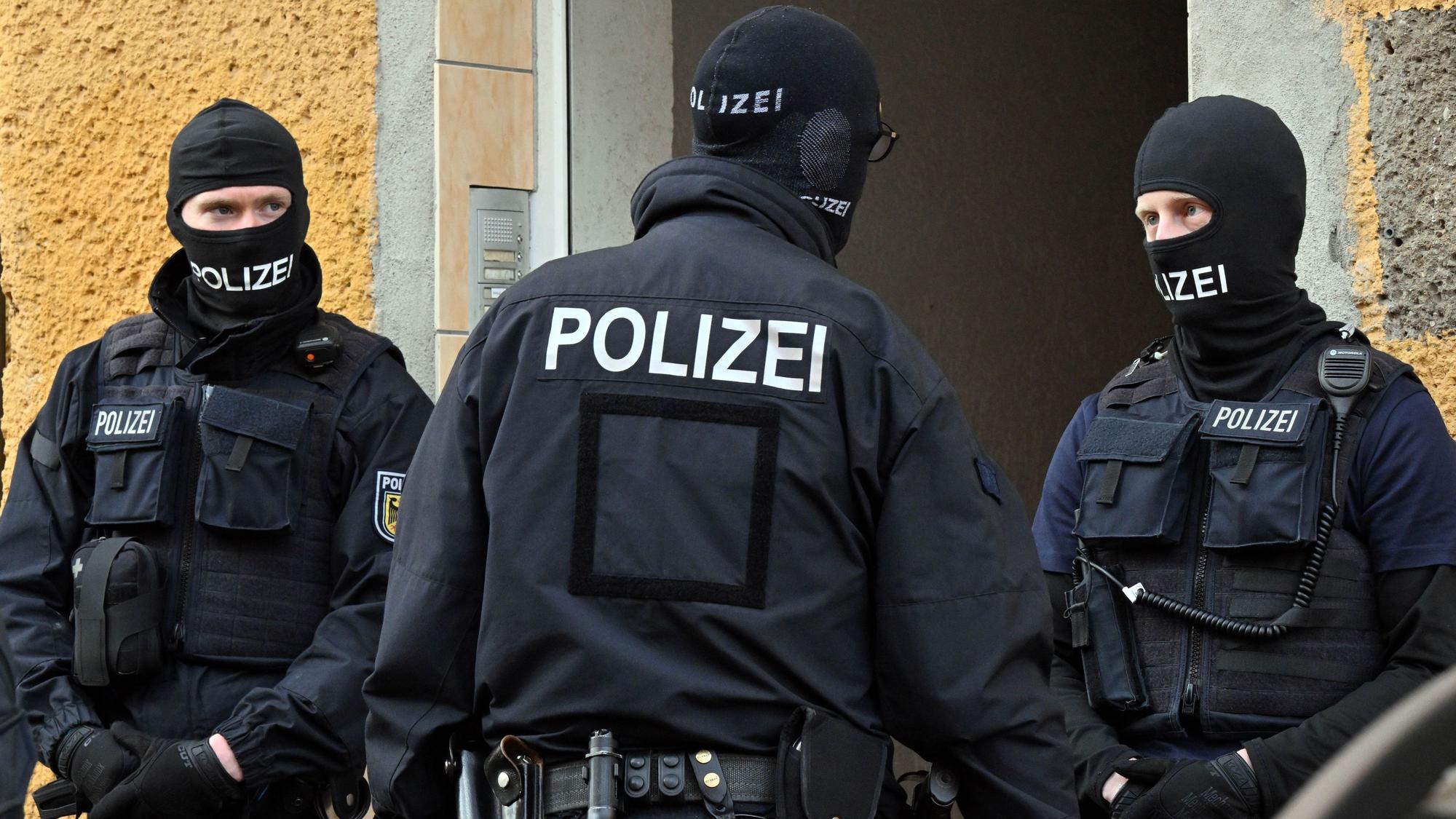 Bundespolizisten stehen vor einem Hauseingang.