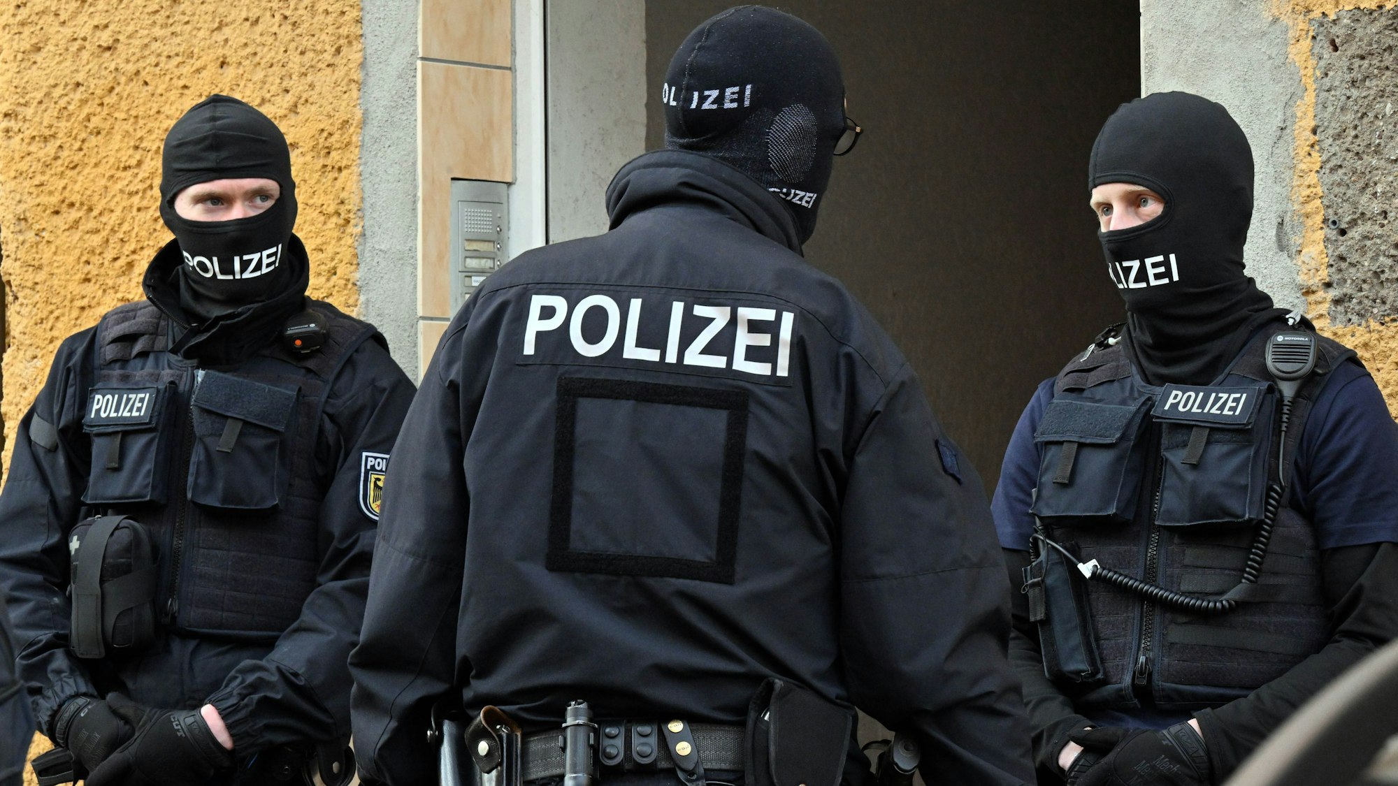Bundespolizisten stehen vor einem Hauseingang.
