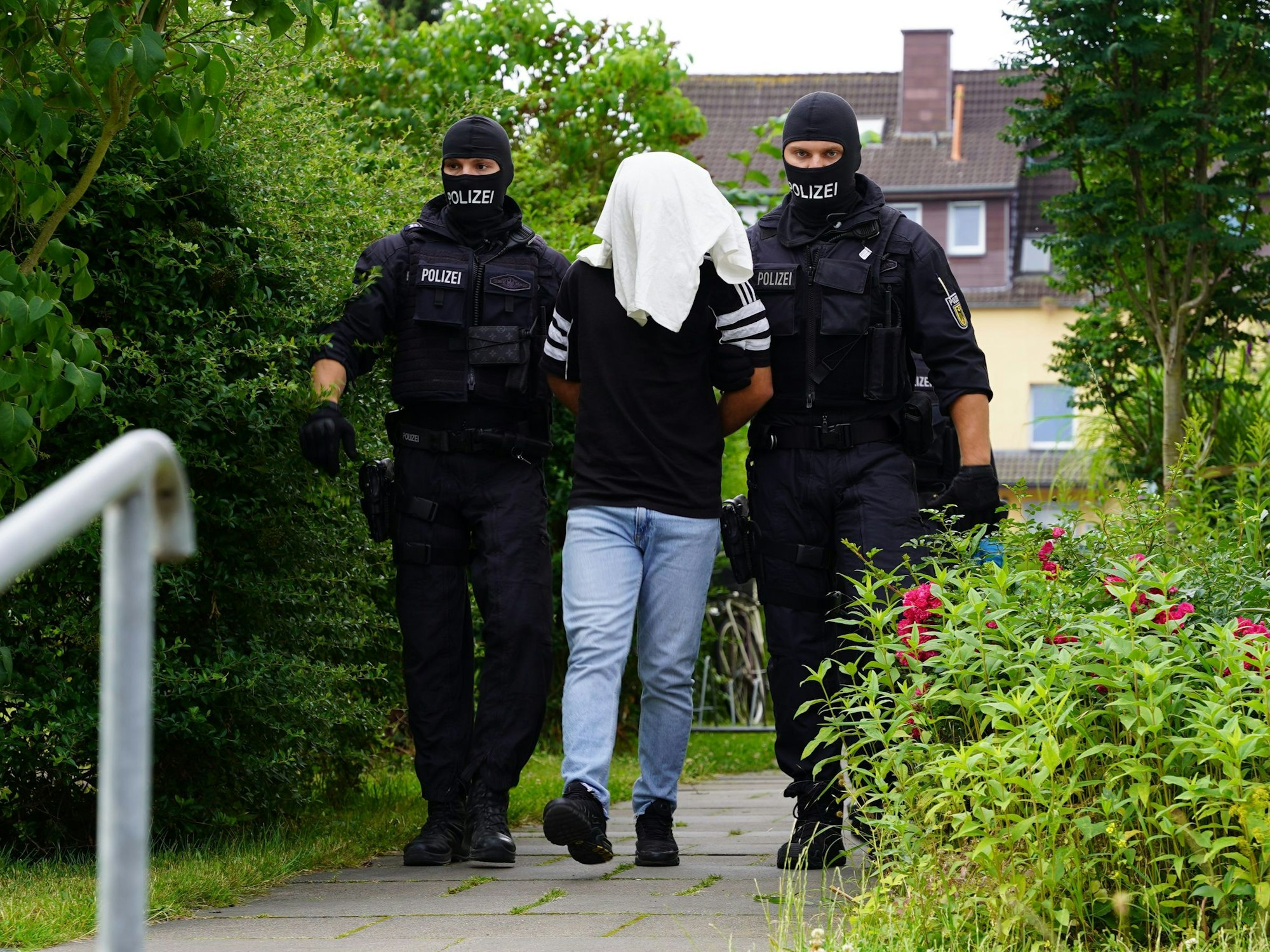 Zwei Polizisten führen einen Mann ab.
