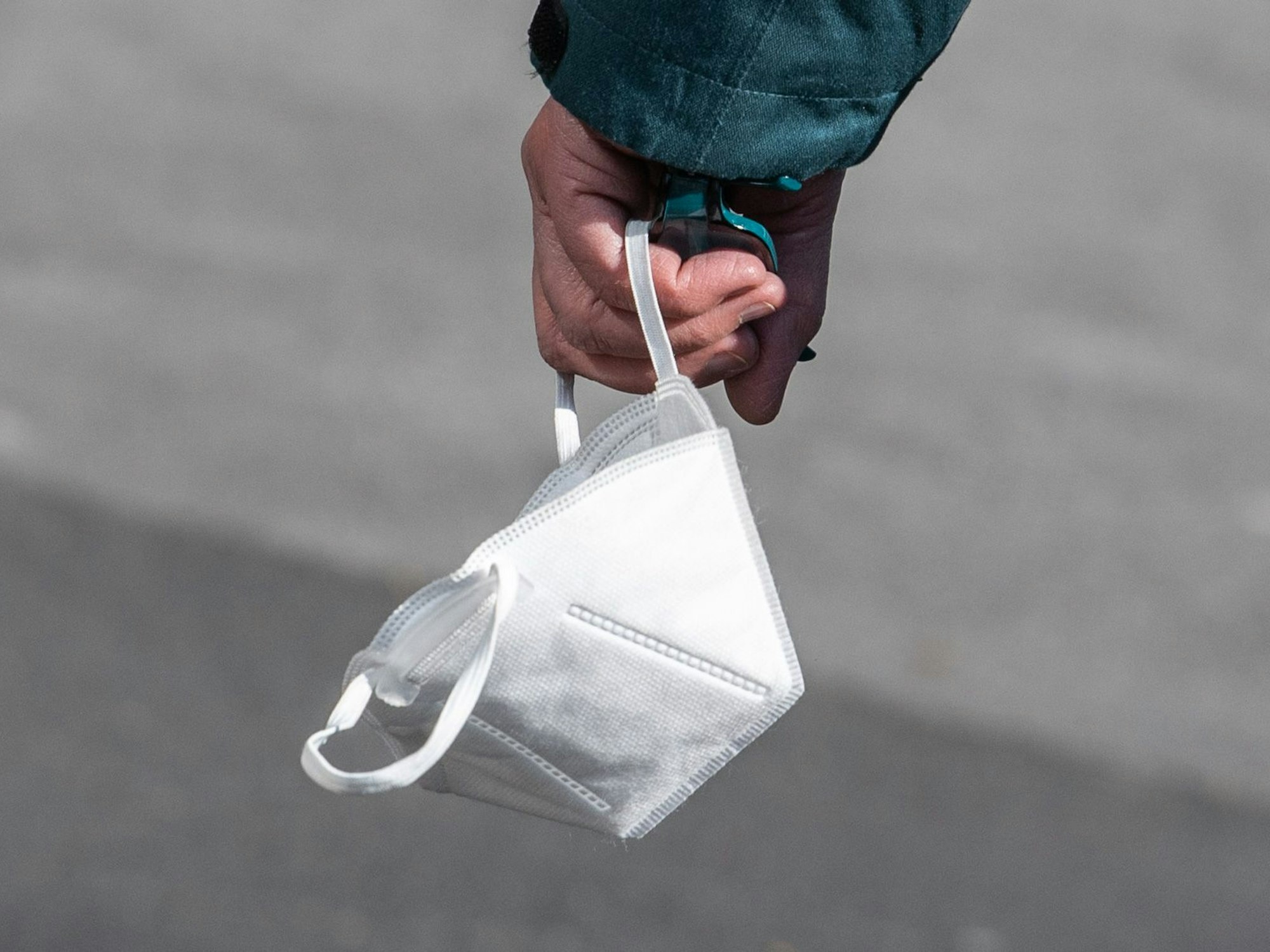 Eine Passantin trägt in der Fußgängerzone von Mainz ihre FFP-2 Maske am Handgelenk.