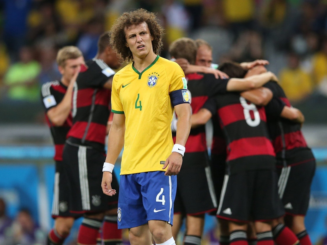 Brasiliens David Luiz schaut geknickt, im Hintergrund jubeln die deutschen Spieler.