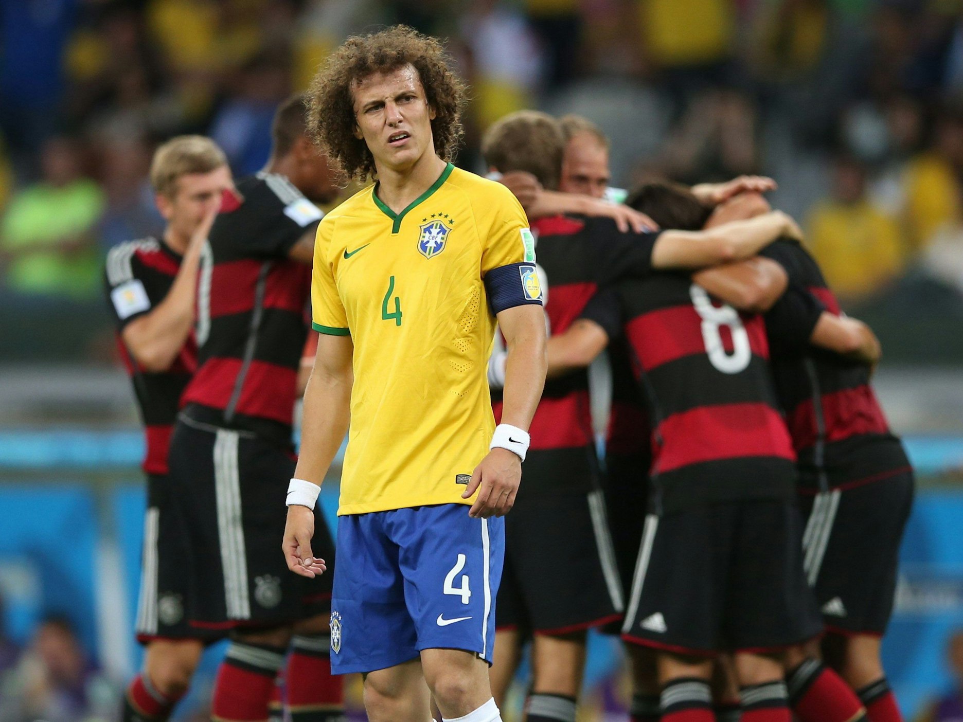 Brasiliens David Luiz schaut geknickt, im Hintergrund jubeln die deutschen Spieler.