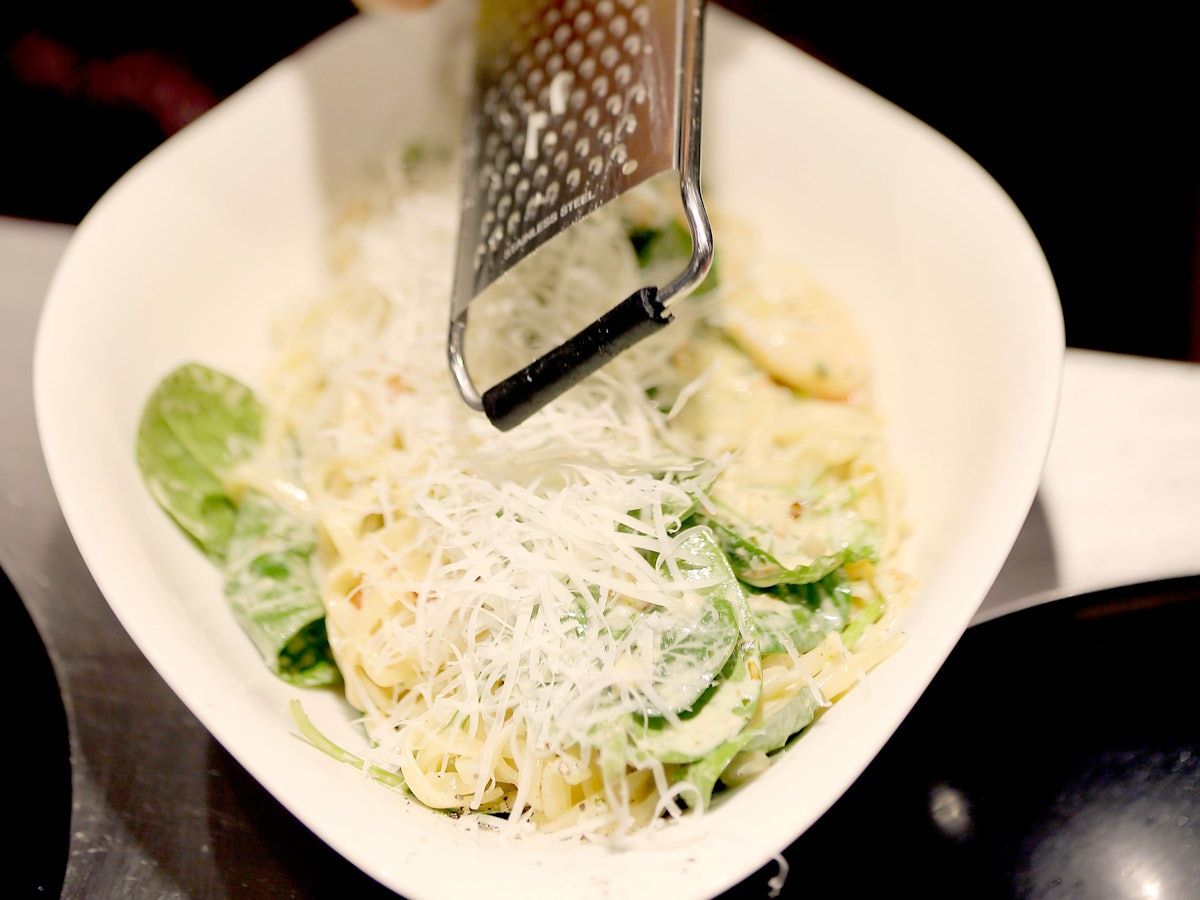 Das Symbolfoto von Parmesan, der über Pasta gerieben wird, wurde 2019 in Köln aufgenommen.