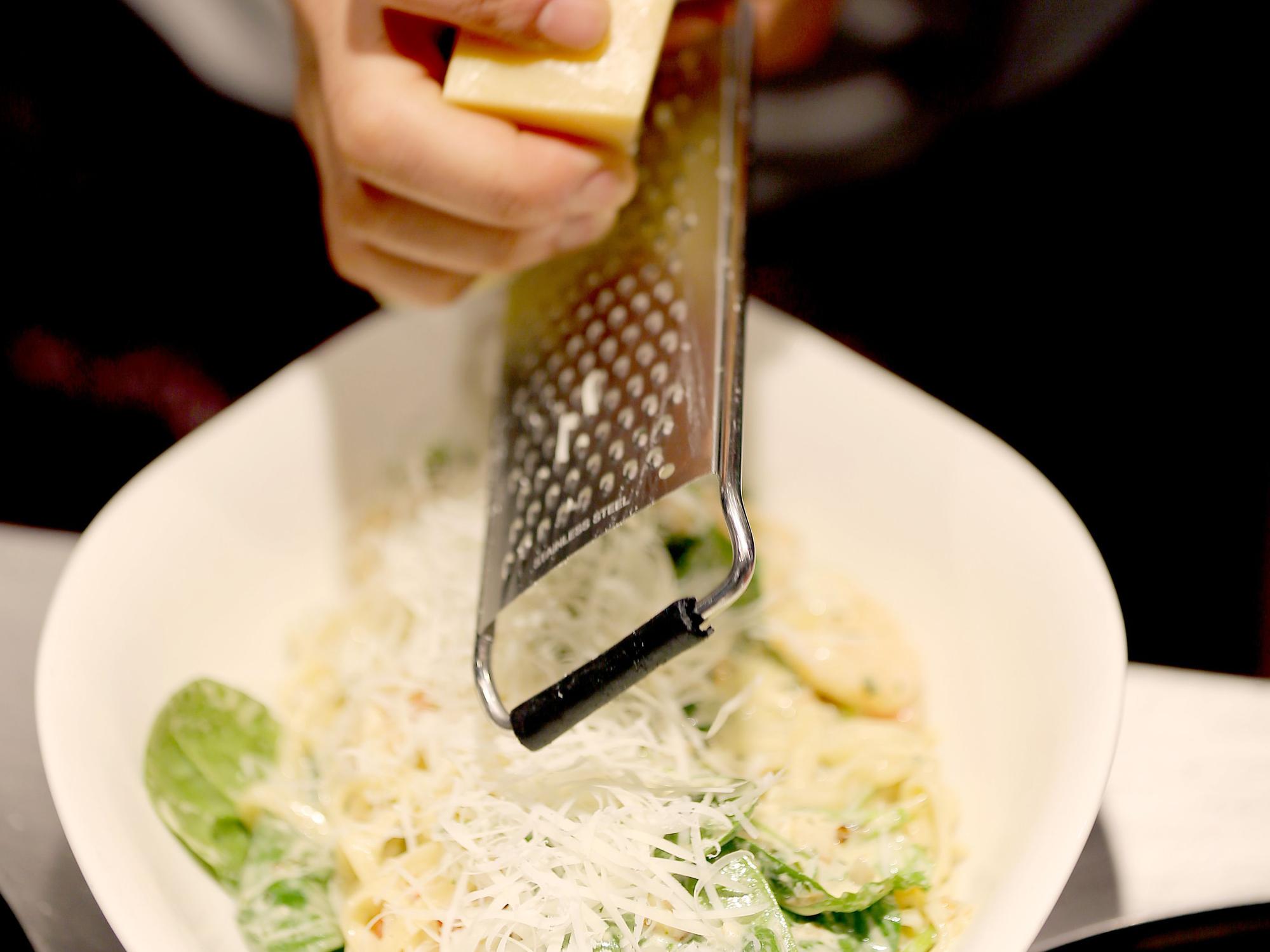 Das Symbolfoto von Parmesan, der über Pasta gerieben wird, wurde 2019 in Köln aufgenommen.