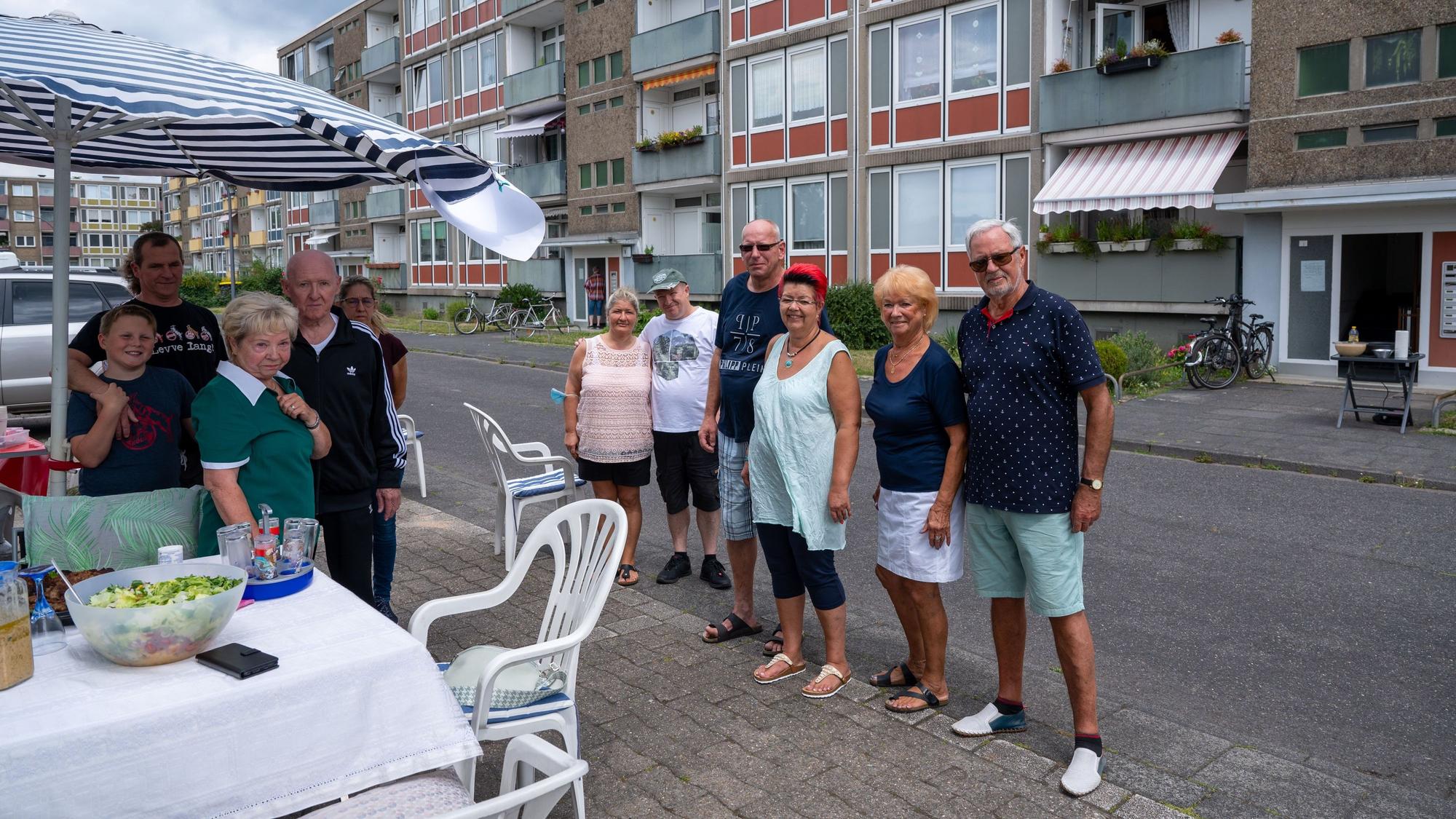 Nachbarschaft steht gemeinsam bei einem Straßenfest und schaut in die Kamera.