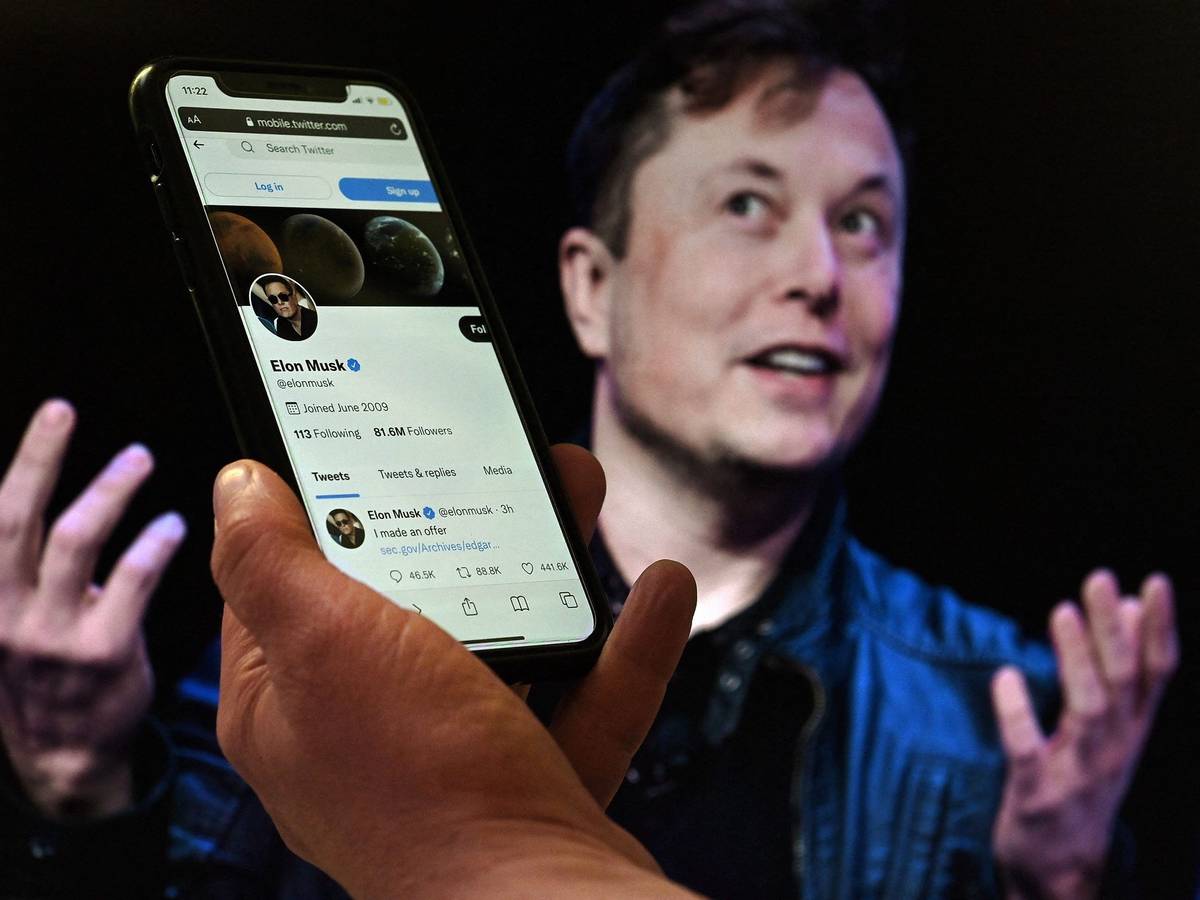 Der Deal zwischen Elon Musk und Twitter scheint geplatzt. Der Tech-Milliardär zweifelt die Unternehmenszahlen an. Twitter will im Notfall klagen. Das Foto eine Hand mit Smartphone, auf dem der Twitter-Account von Elon Musk. Im Hintergrund ist er selbst zu sehen.