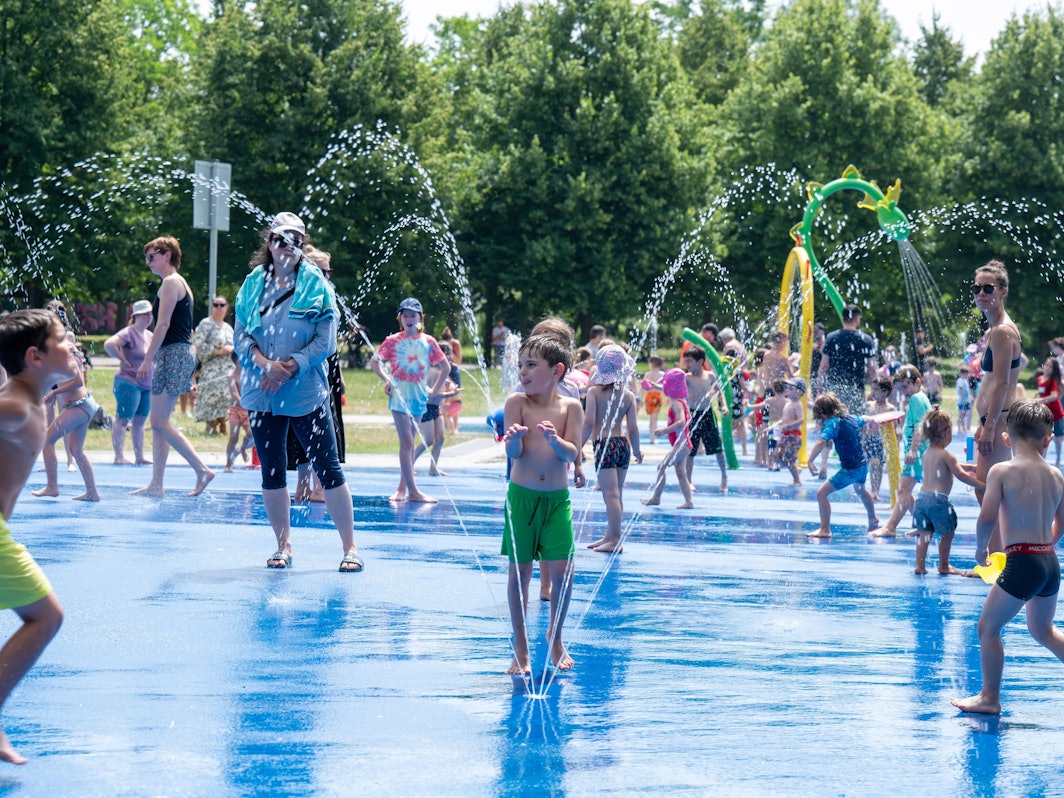 Kinder spielen mit einer Wasserfontäne.