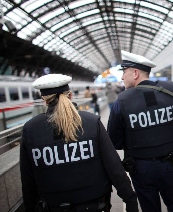 Zwei Einsatzkräfte der Bundespolizei gehen einen Bahnsteig im Kölner Hauptbahnhof entlang, neben ihnen steht ein ICE.