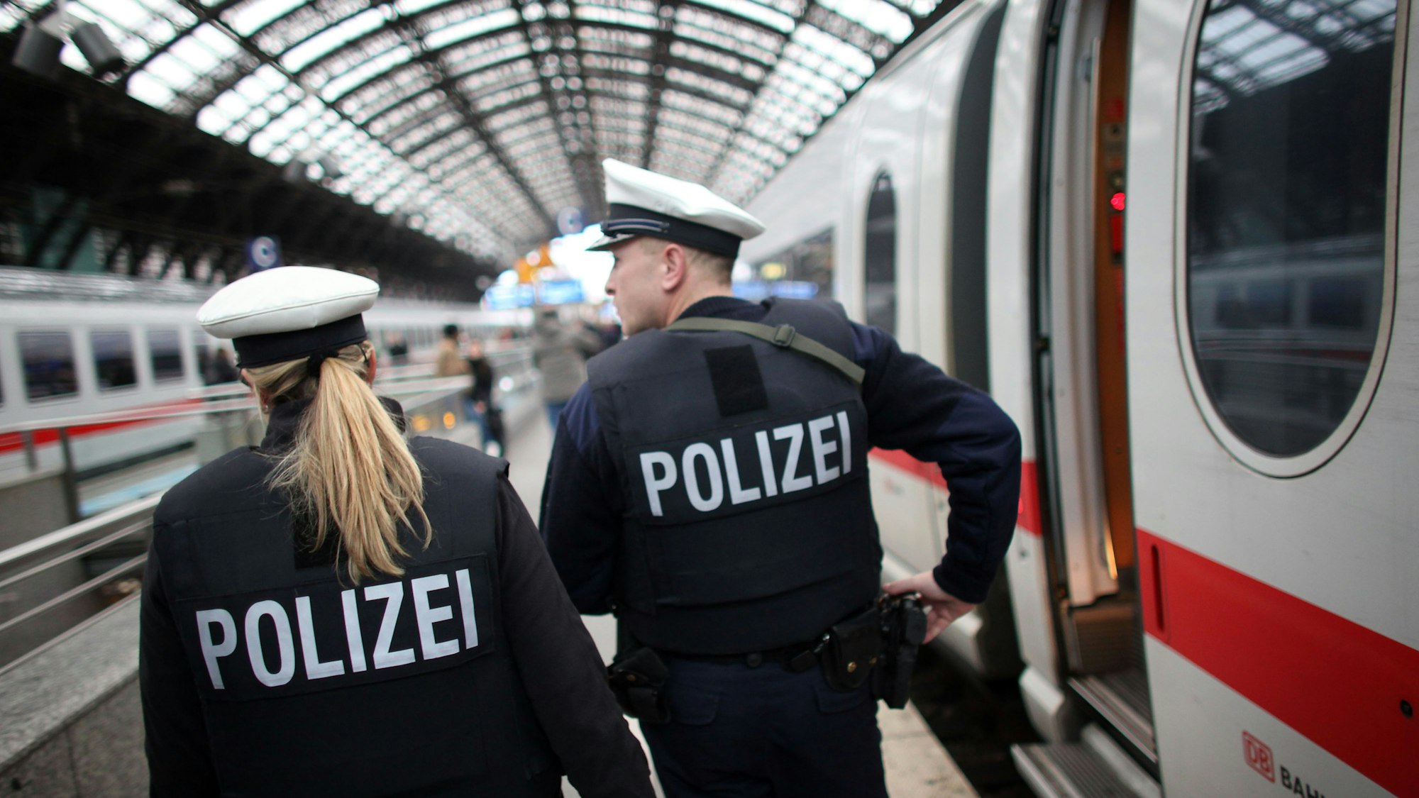 Bundespolizisten patrouillieren im Kölner Hauptbahnhof, an einem Gleis steht ein ICE.