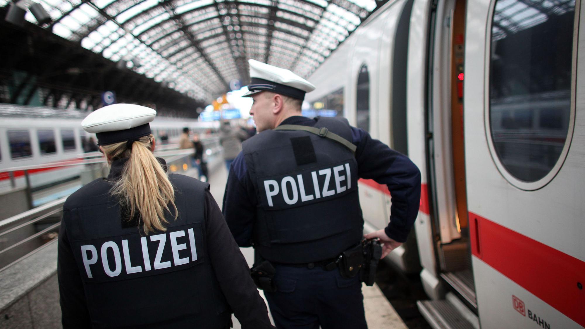 Eine Bundespolizistin und ein Bundespolizist patrouillieren auf einem Bahnsteig des Kölner Hauptbahnhofs, an dem ein ICE gehalten hat.