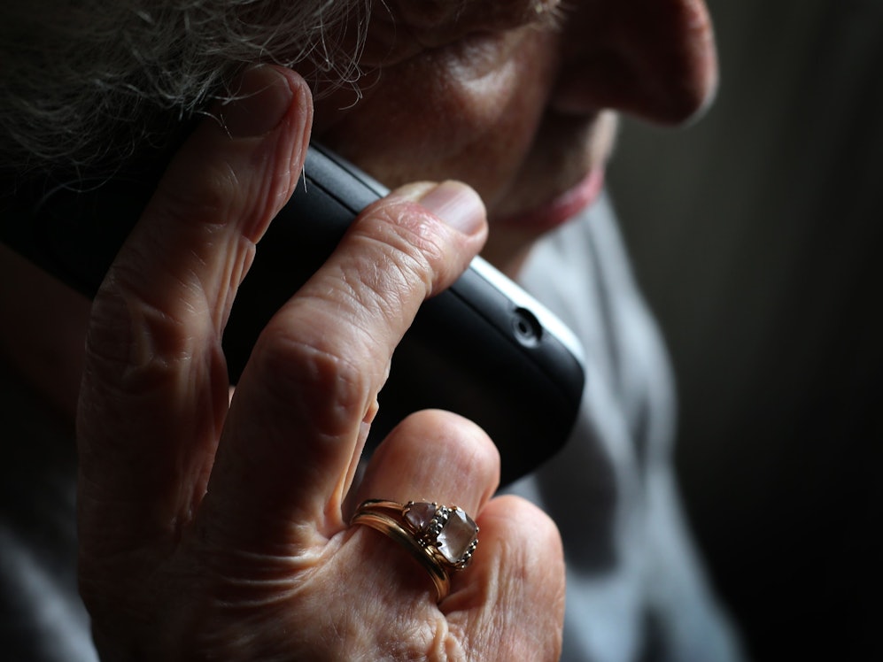Eine ältere Frau telefoniert mit einem schnurlosen Festnetztelefon.
