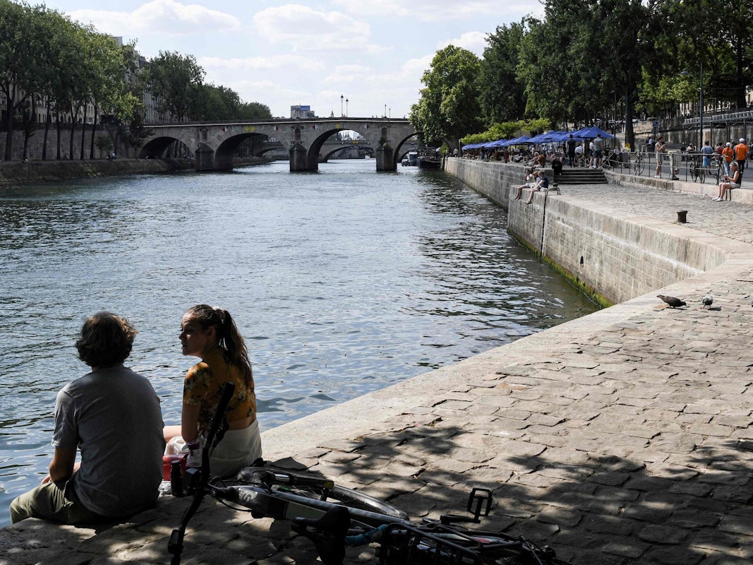 Ein Paar sitzt an dem Ufer der Seine. Entlang der Seine in Paris lockt der über den Sommer eingerichtete Stadtstrand seit Samstag wieder mit Freizeit- und Kulturaktivitäten.