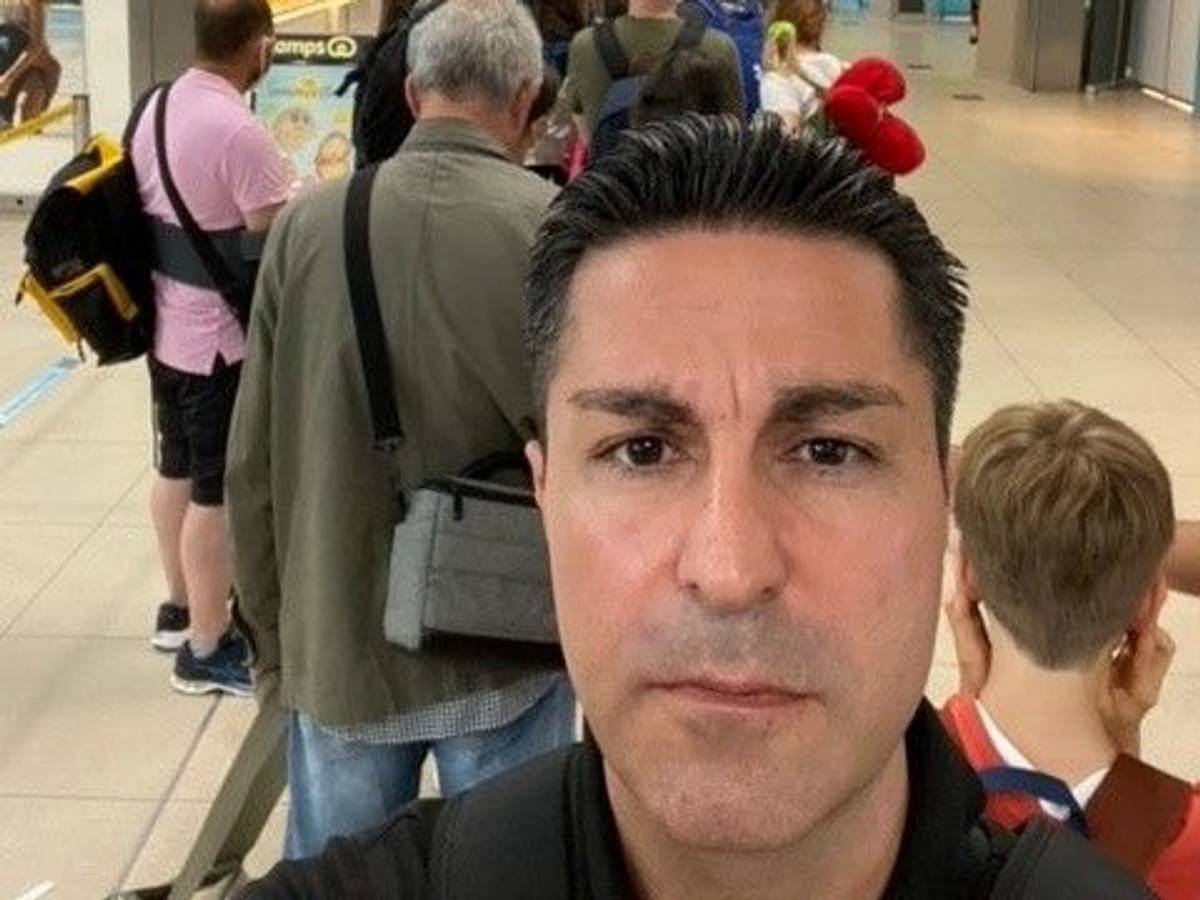 Ein Mann macht ein Selfie in einer Warteschlange.