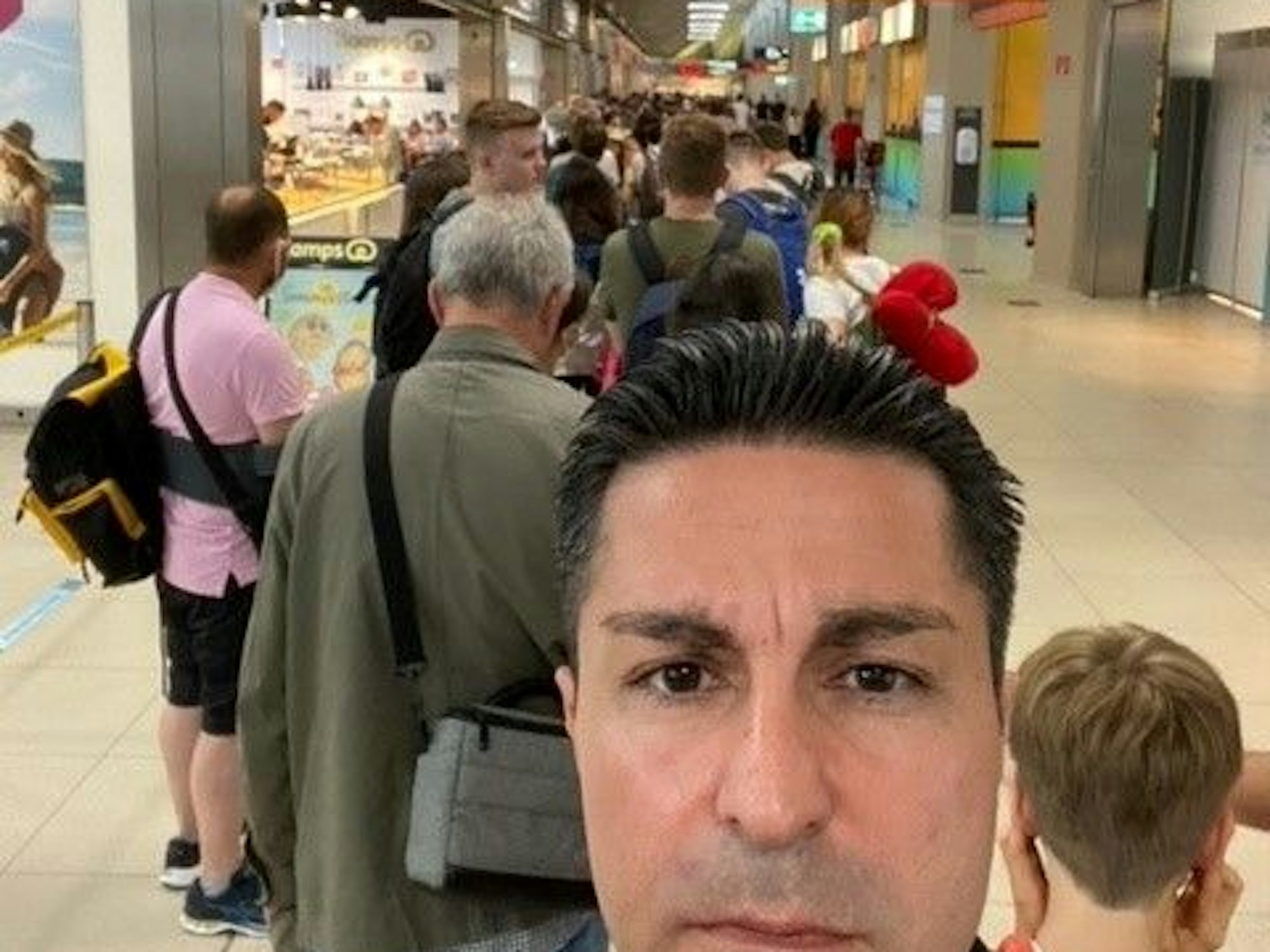 Ein Mann macht ein Selfie in einer Warteschlange.
