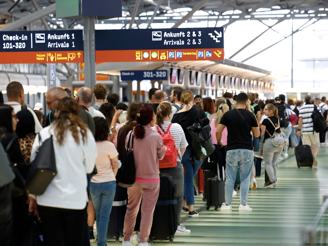 Passagiere stehen in einer Schlange von mehreren hundert Metern für die Sicherheitskontrolle am Flughafen Köln-Bonn an.