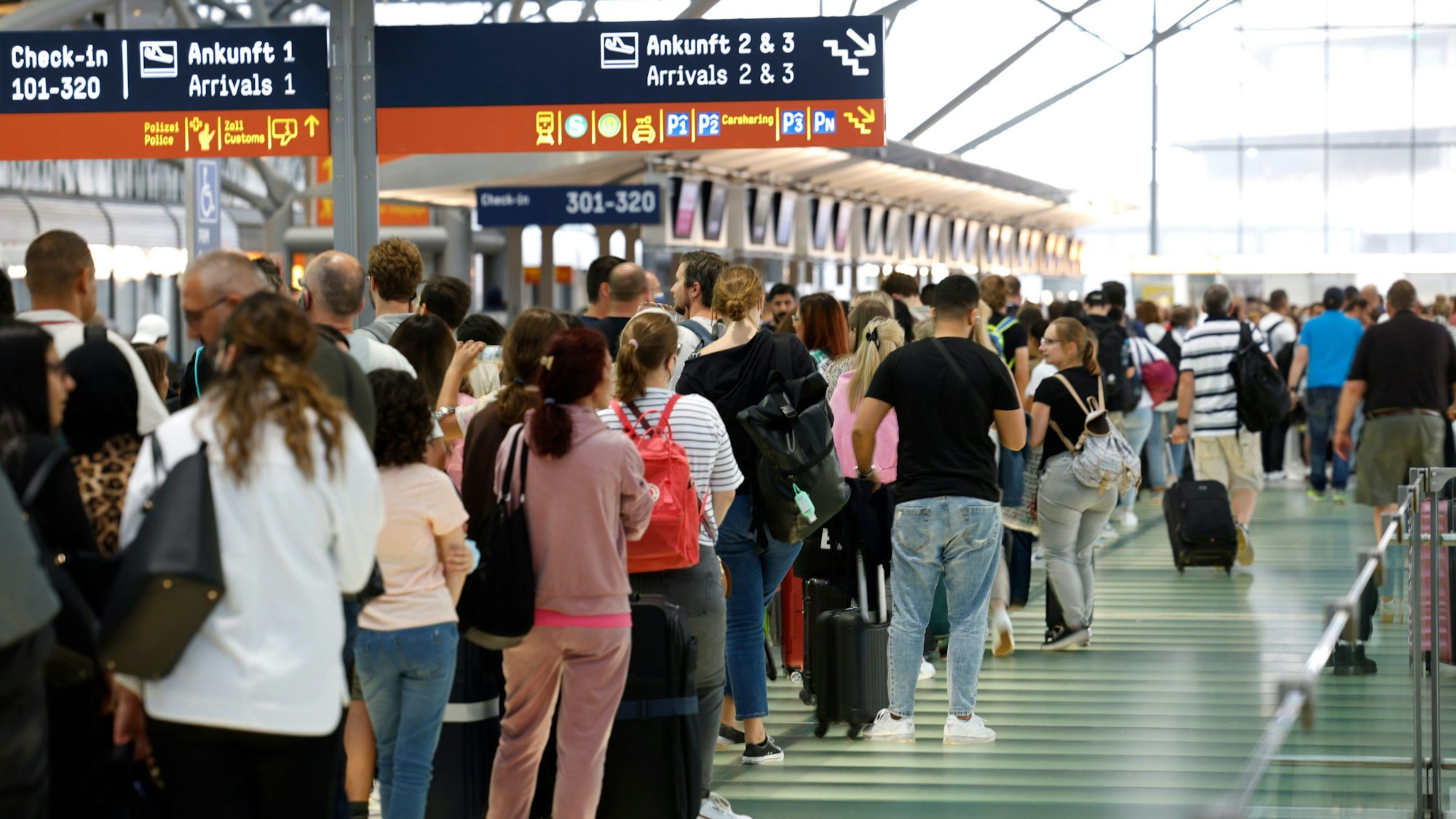 Passagiere stehen in einer Schlange von mehreren hundert Metern für die Sicherheitskontrolle am Flughafen Köln-Bonn an.