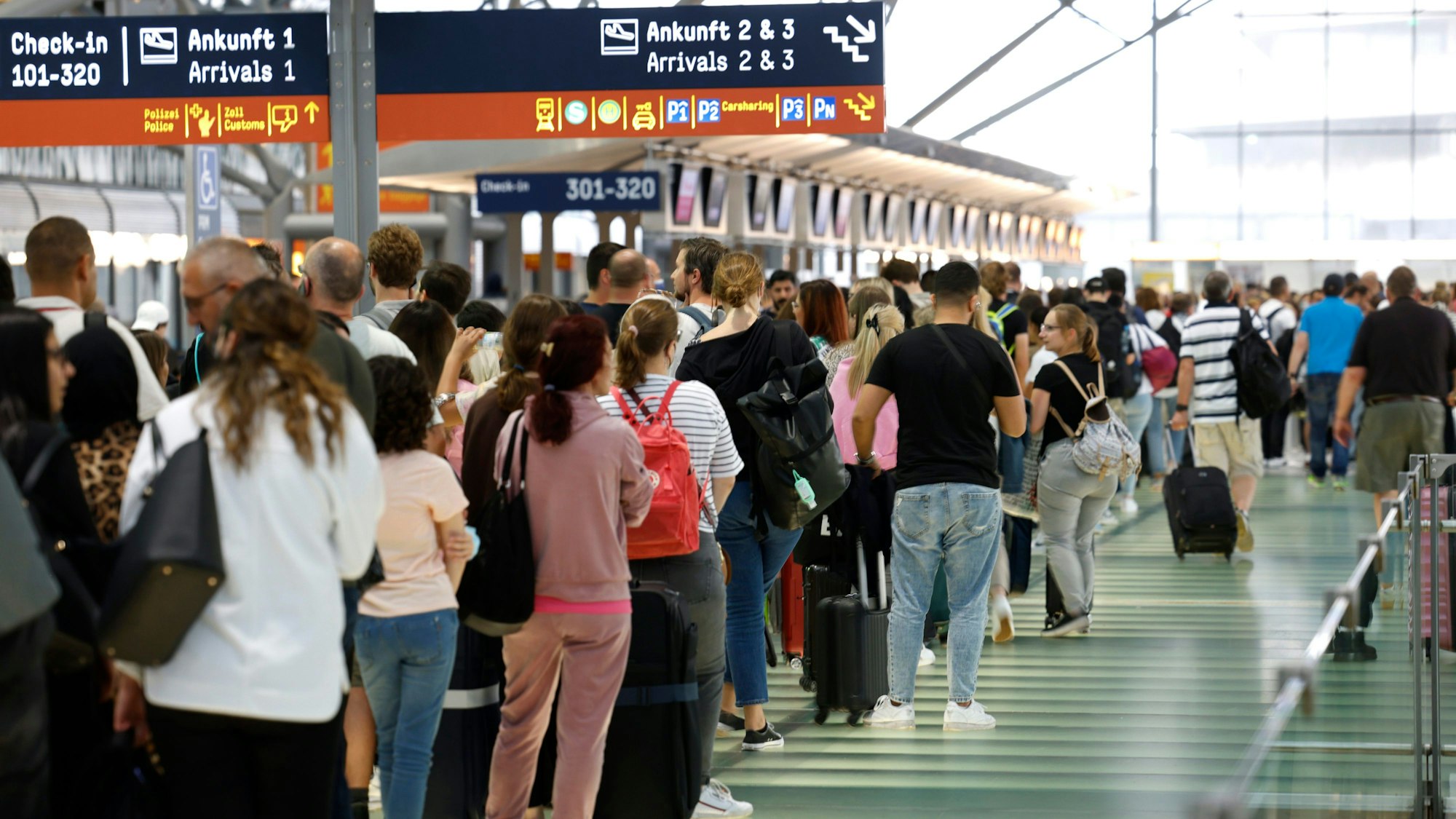 Passagiere stehen in einer Schlange von mehreren hundert Metern für die Sicherheitskontrolle am Flughafen Köln-Bonn an.