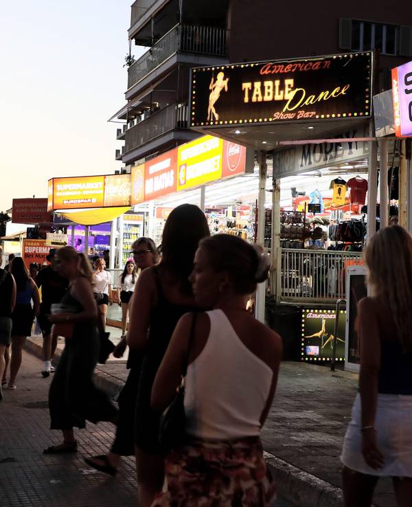 Palma: Menschen spazieren auf der Strandpromenade von Arenal auf Mallorca an Show-Bars vorbei.