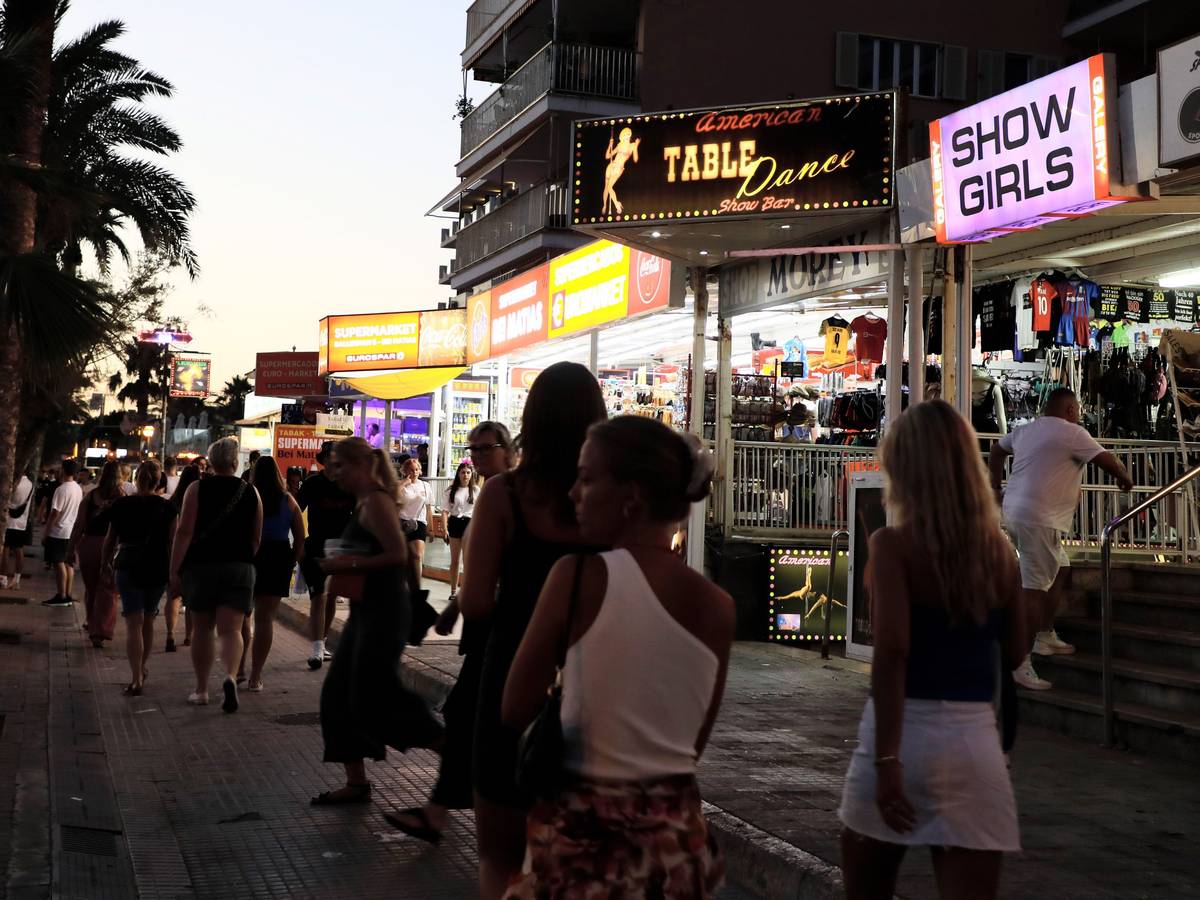 Palma: Menschen spazieren auf der Strandpromenade von Arenal auf Mallorca an Show-Bars vorbei.